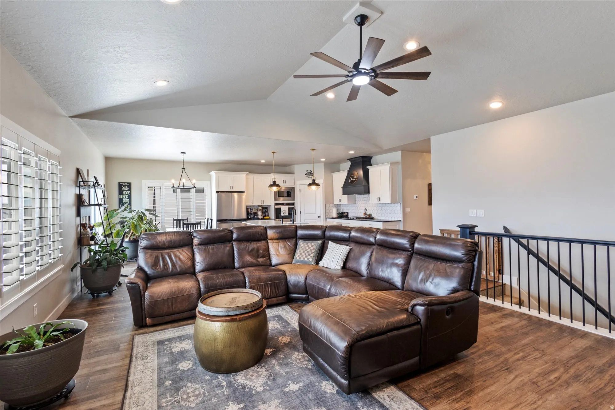 Living area featuring ceiling fan, wood finished floors, a chandelier, and lofted ceiling