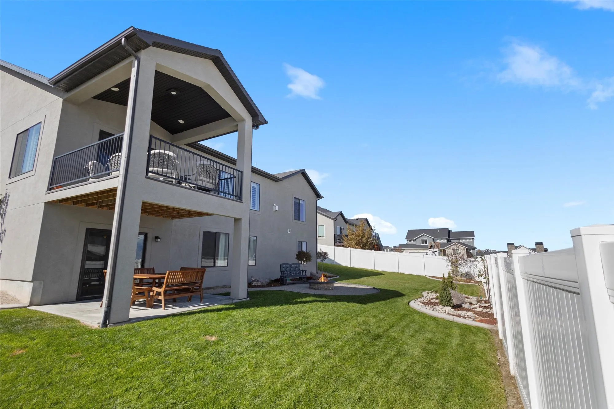Back of property with a patio area, stucco siding, a fenced backyard, an outdoor fire pit, and a balcony