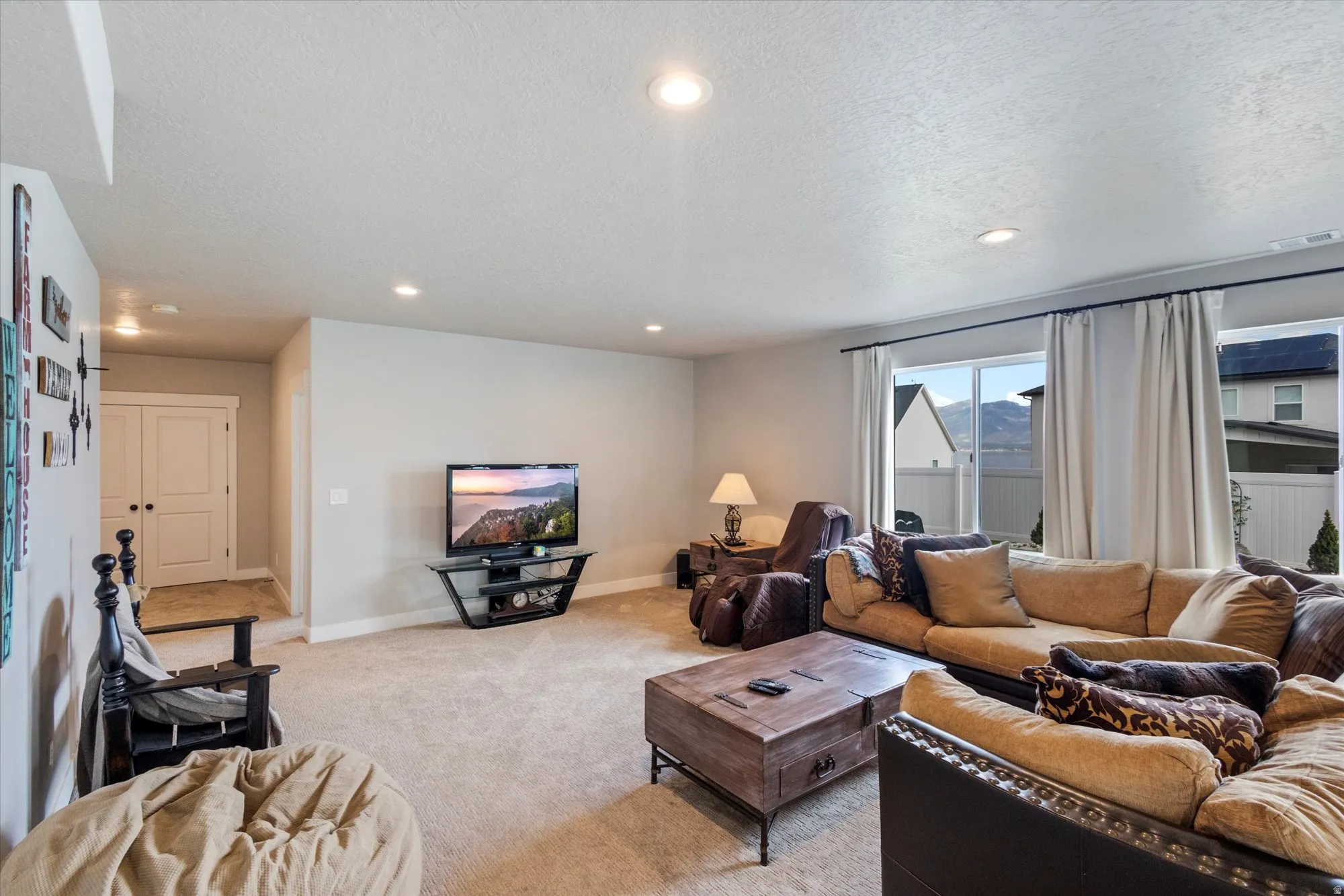 Living area with a textured ceiling, recessed lighting, and light carpet