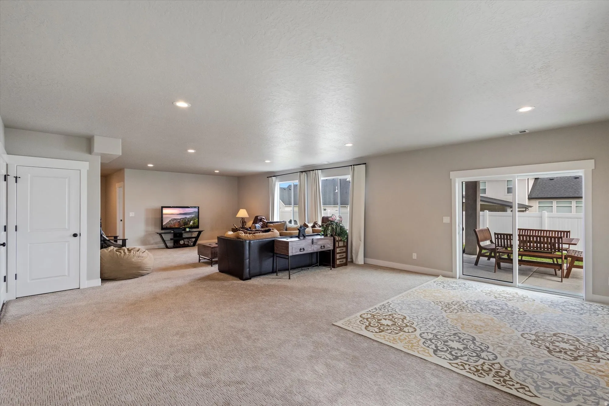 Living area with light carpet, recessed lighting, and a textured ceiling