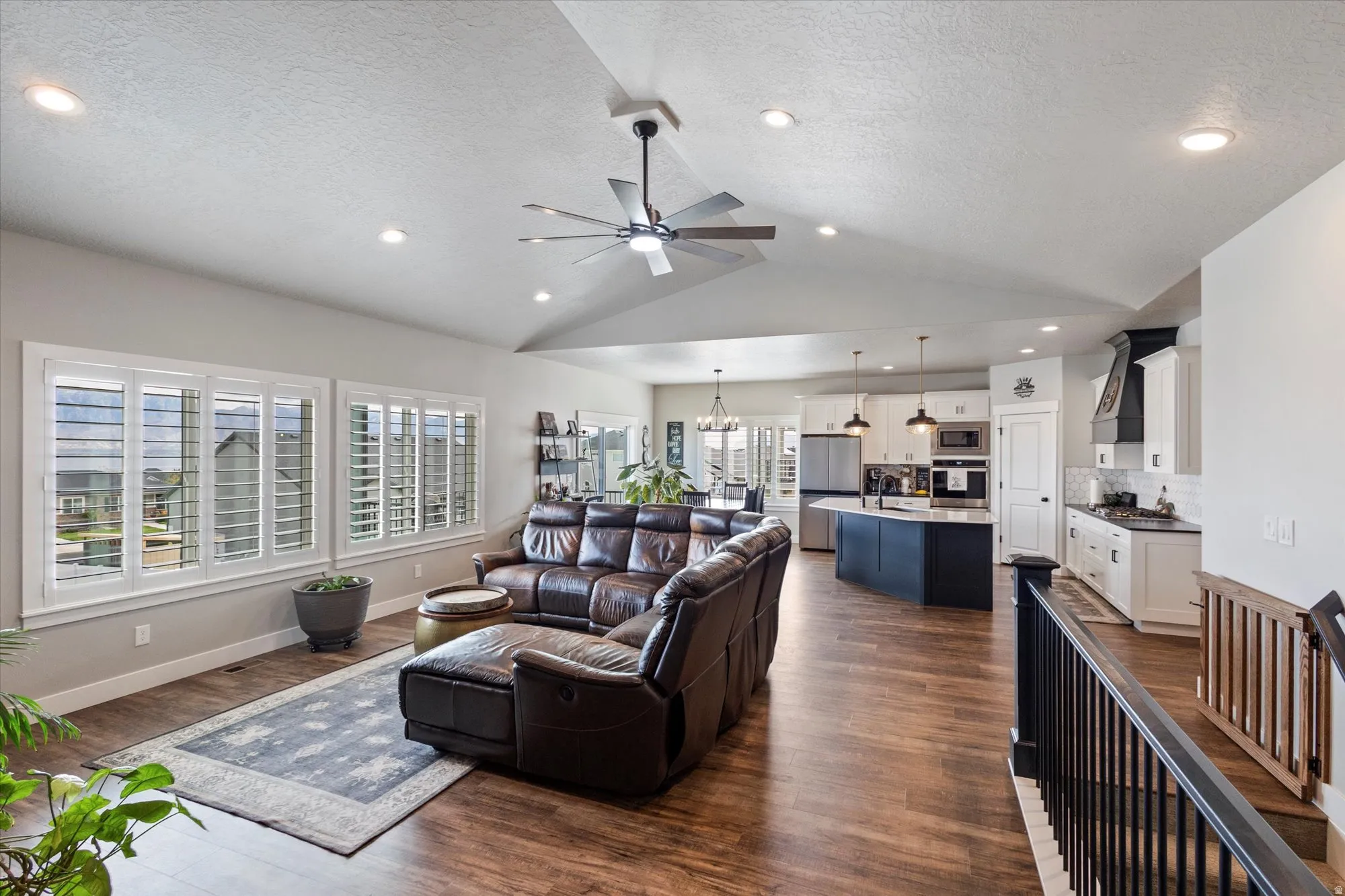 Living room with a ceiling fan, dark wood-type flooring, and a chandelier
