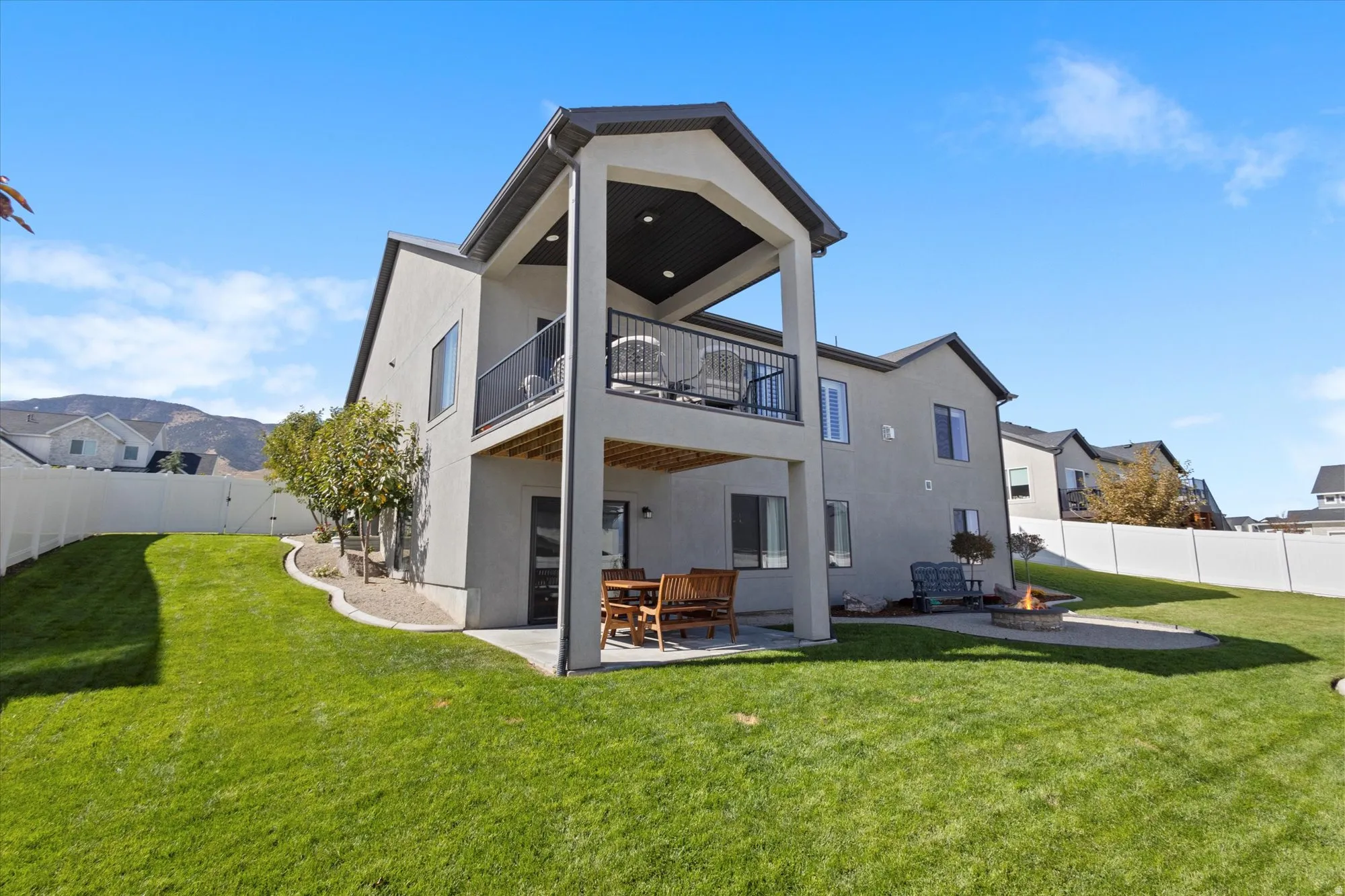 Rear view of house with a patio, a fenced backyard, stucco siding, and a balcony