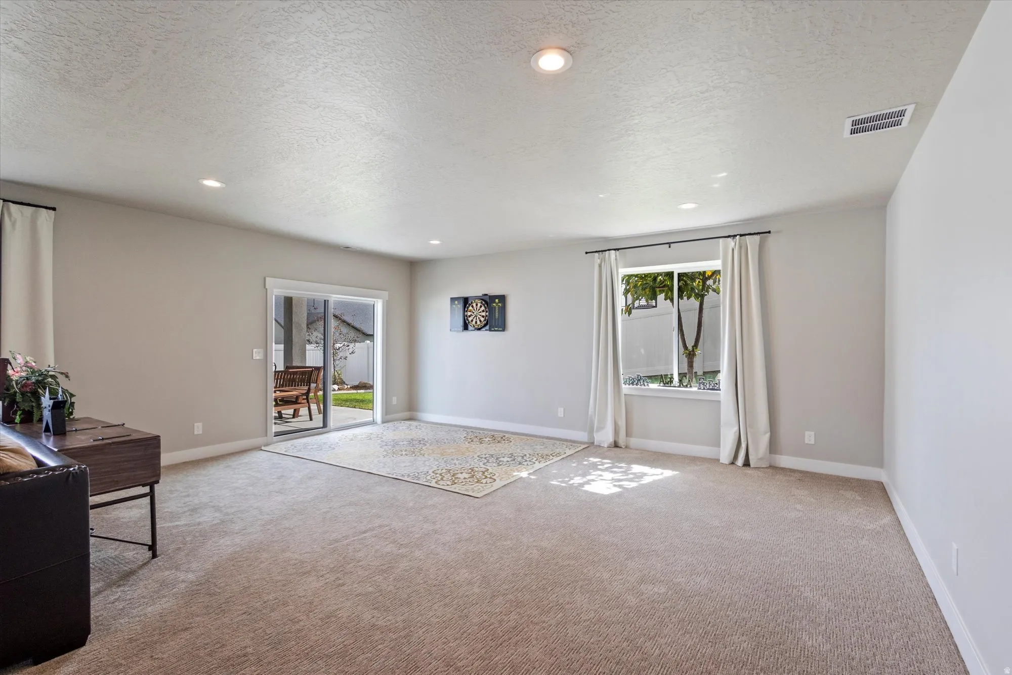 Living area featuring a textured ceiling, light colored carpet, and recessed lighting