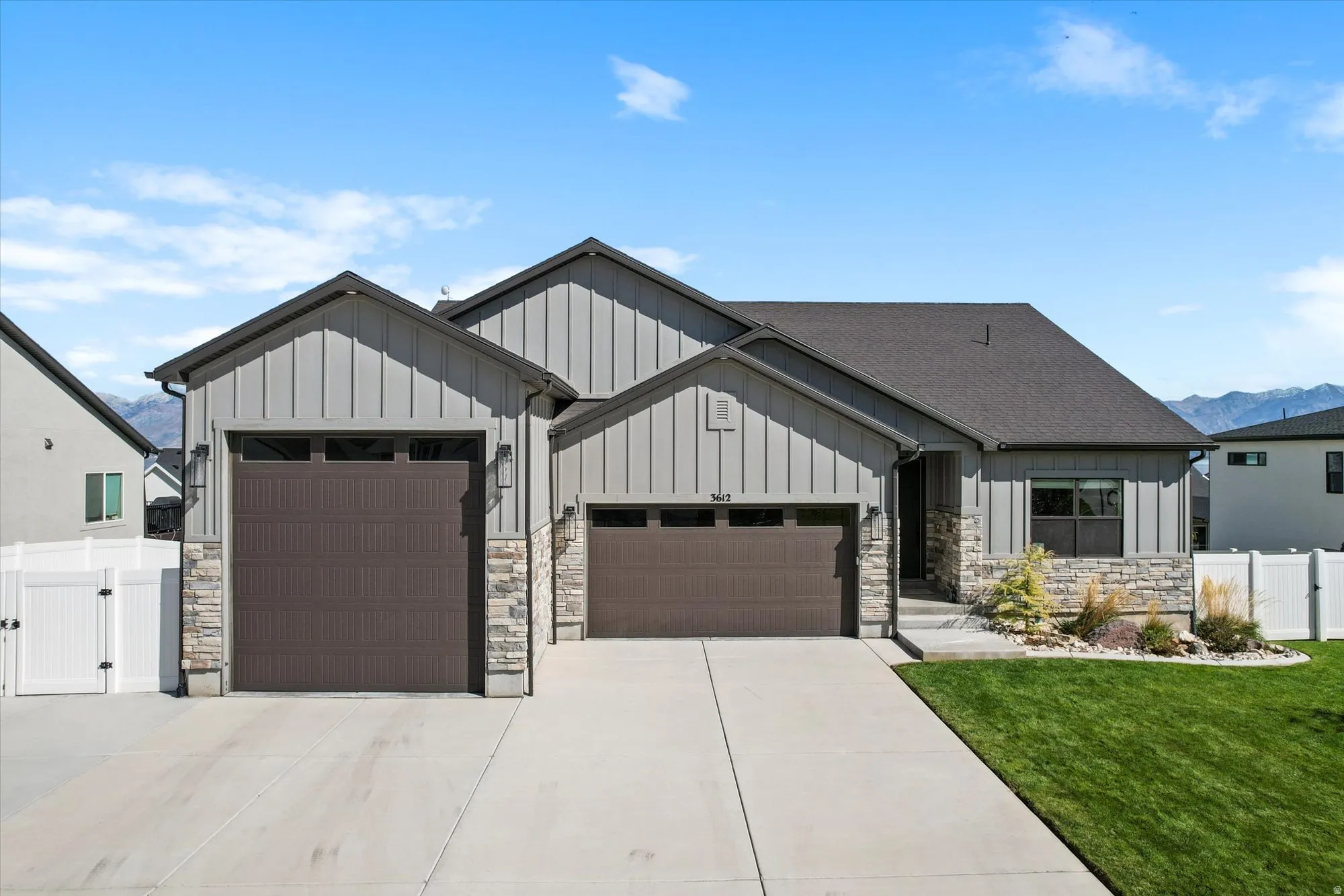 Modern farmhouse style home featuring board and batten siding, a gate, a garage, driveway, and a mountain view