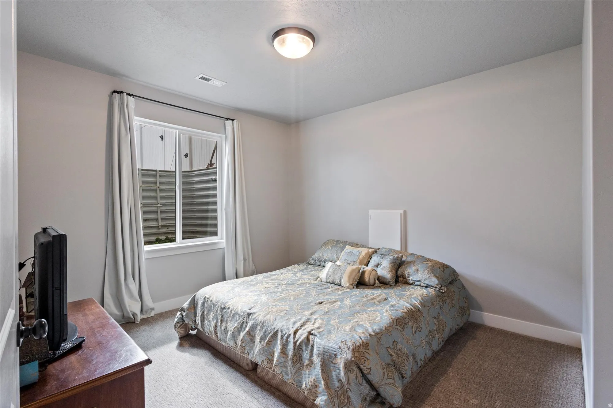 Carpeted bedroom with baseboards and a textured ceiling