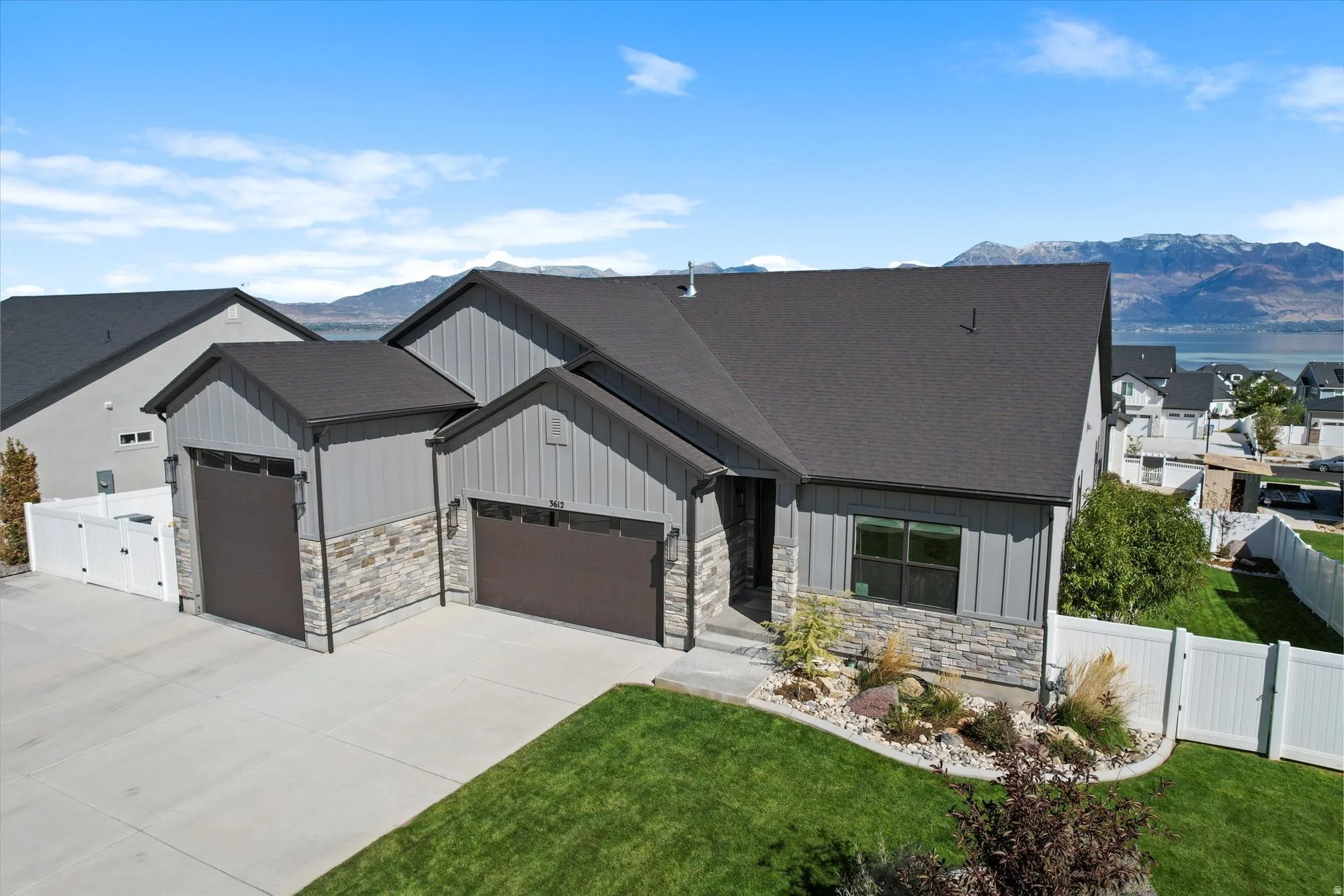 Modern farmhouse style home featuring board and batten siding, a mountain view, an attached garage, and a gate