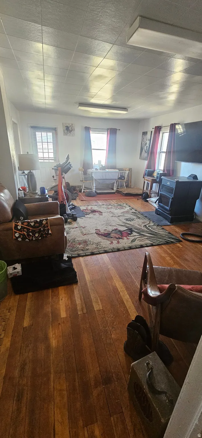 Living area featuring dark wood finished floors, healthy amount of natural light, and a wood stove