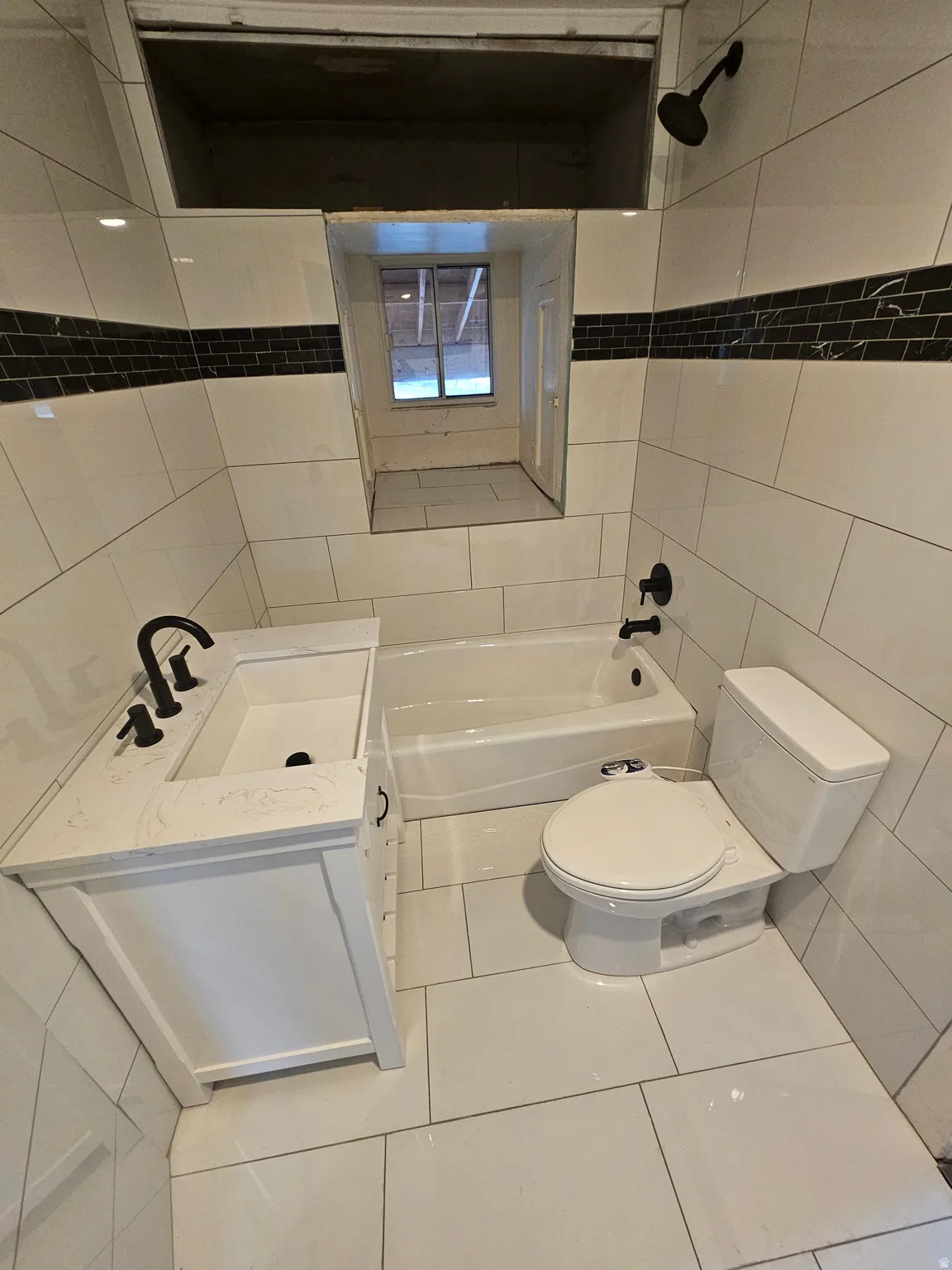 Bathroom featuring tile walls, vanity, bathtub / shower combination, and tile patterned flooring