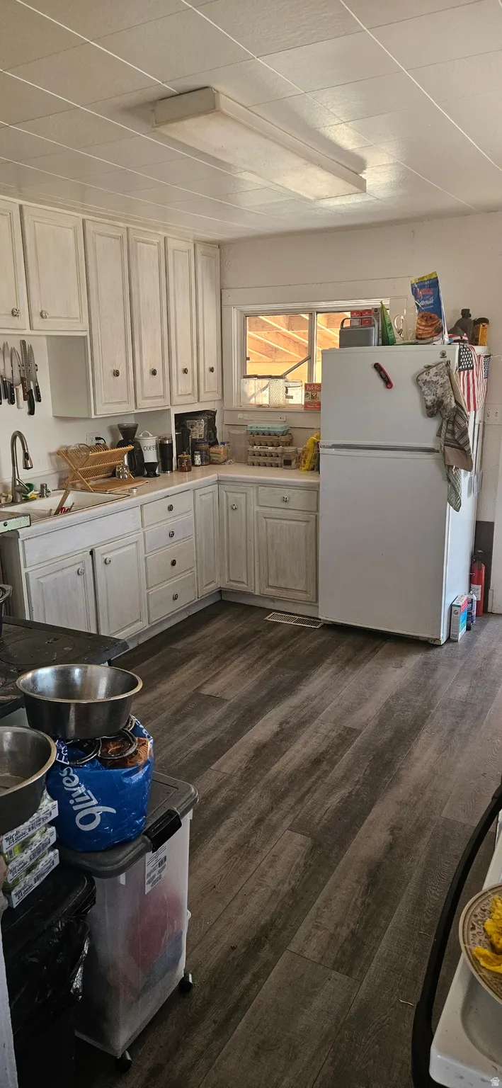 Kitchen featuring freestanding refrigerator, dark wood-type flooring, and light countertops