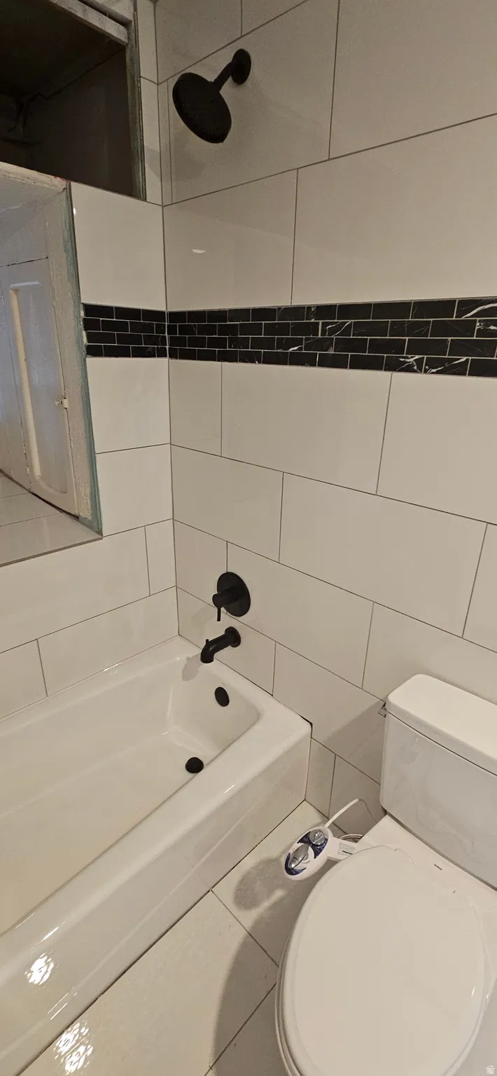 Bathroom with washtub / shower combination and tile walls