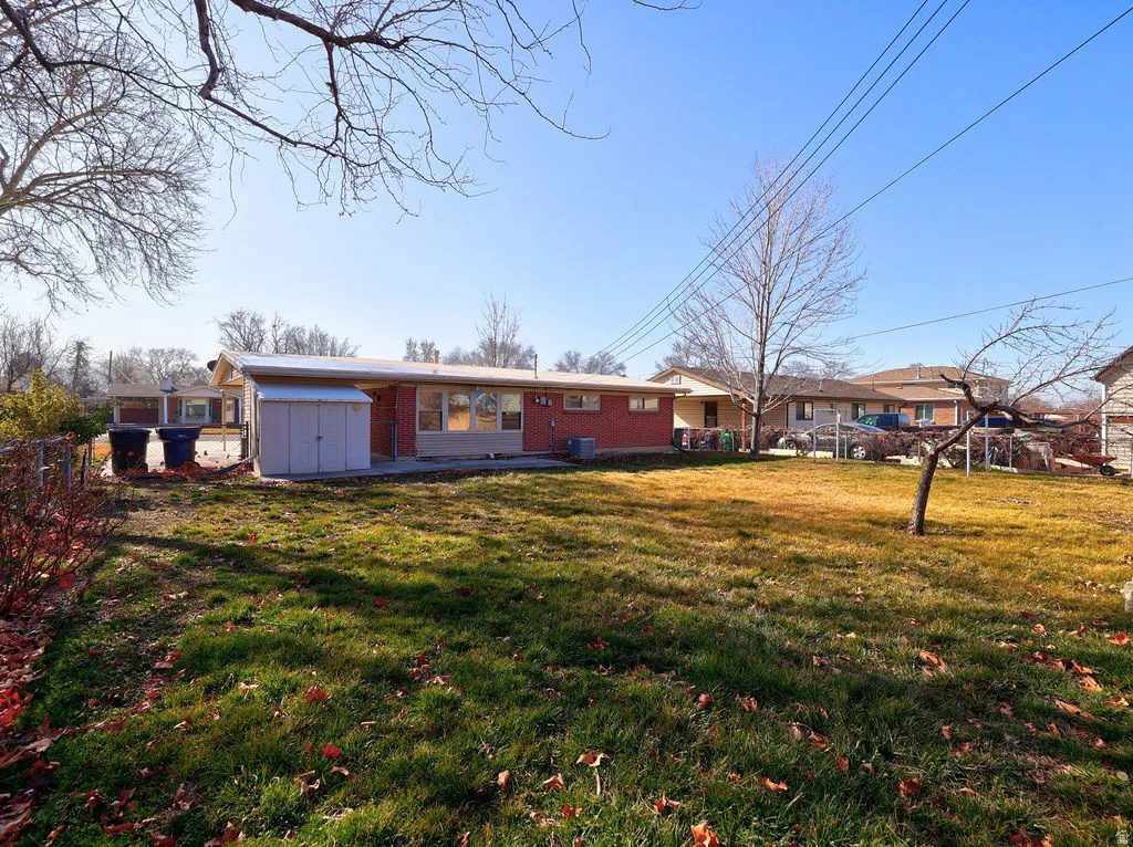 Rear view of house with a shed, brick siding, and a patio area