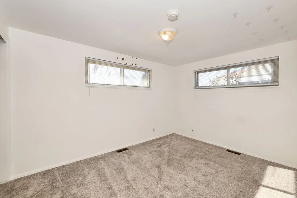 Carpeted empty room featuring baseboards and a smoke detector