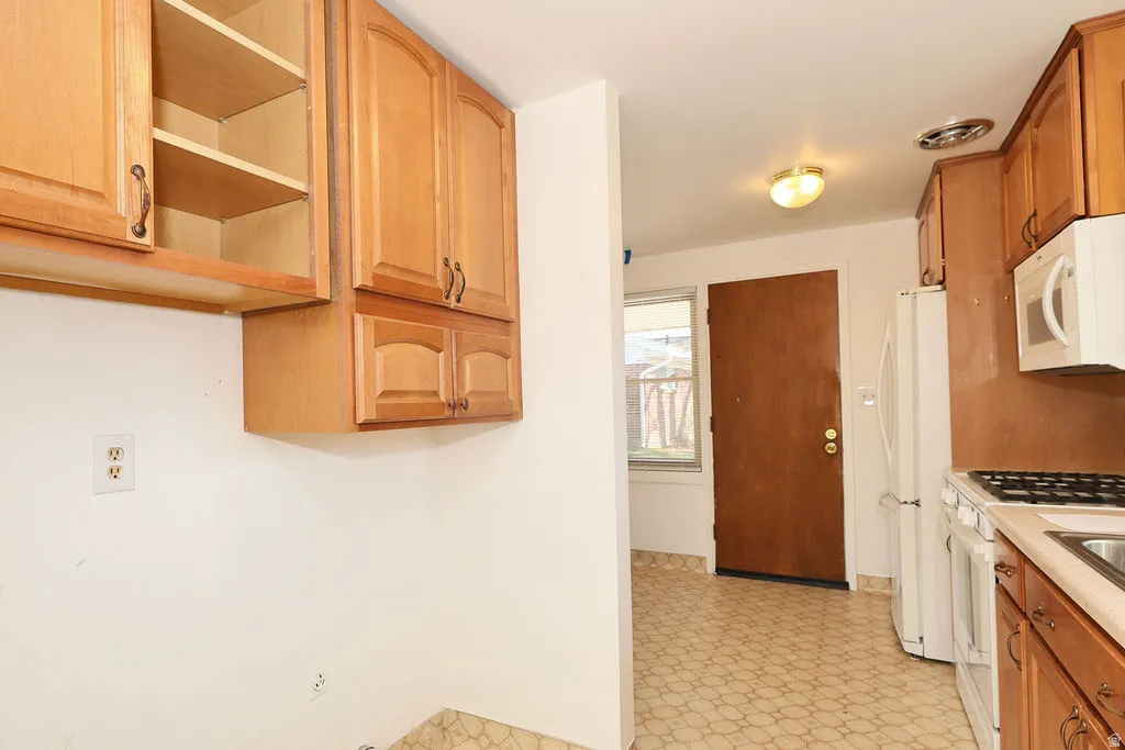 Kitchen featuring light floors, white appliances, light countertops, and wood finish cabinetry
