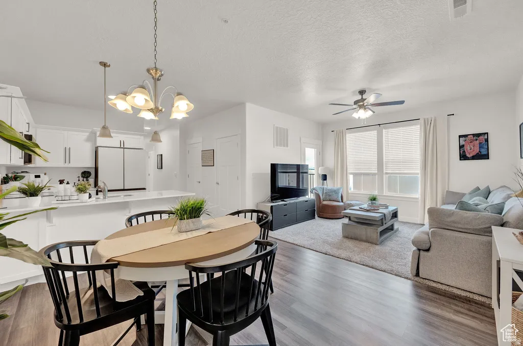Dining room featuring suspended lighting, light wood-type flooring, a ceiling fan, and a textured ceiling