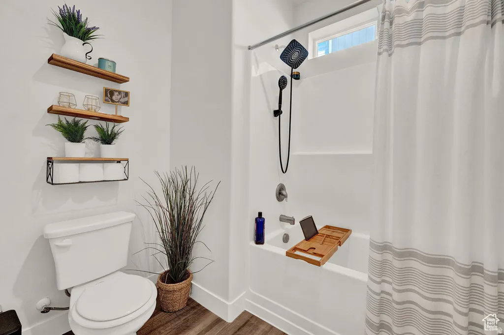 Bathroom with shower / tub combo with curtain and dark wood-style flooring