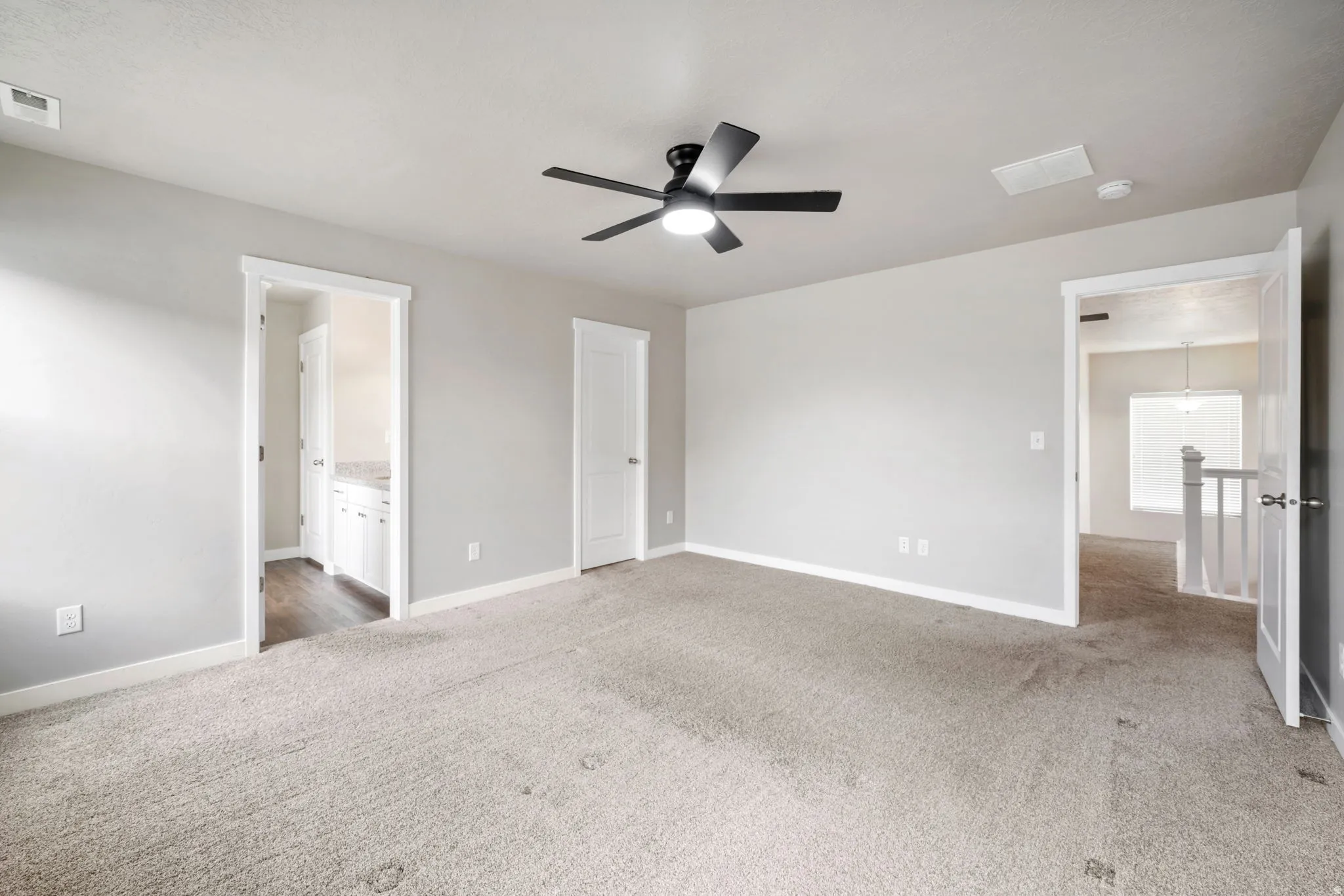 Unfurnished bedroom featuring light colored carpet, ceiling fan, and connected bathroom