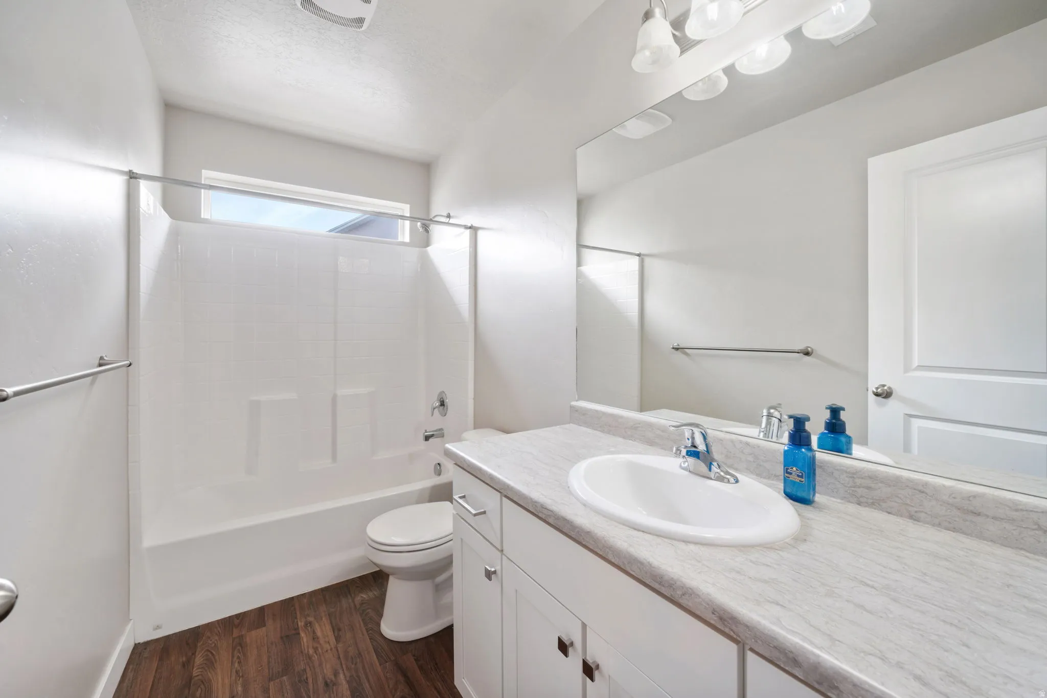 Full bath featuring vanity, dark wood-style floors, and washtub / shower combination