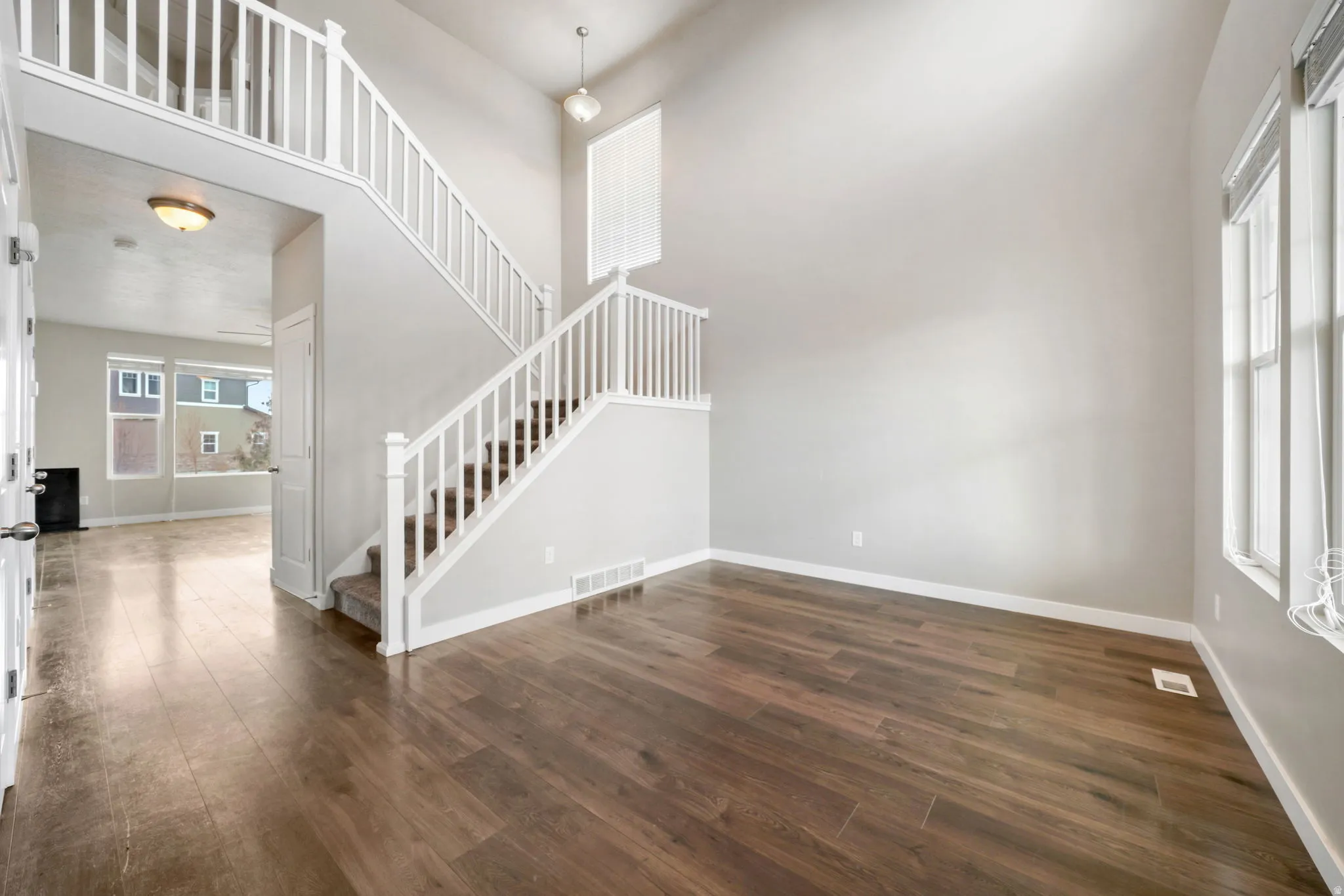 Unfurnished living room featuring dark wood finished floors and a high ceiling