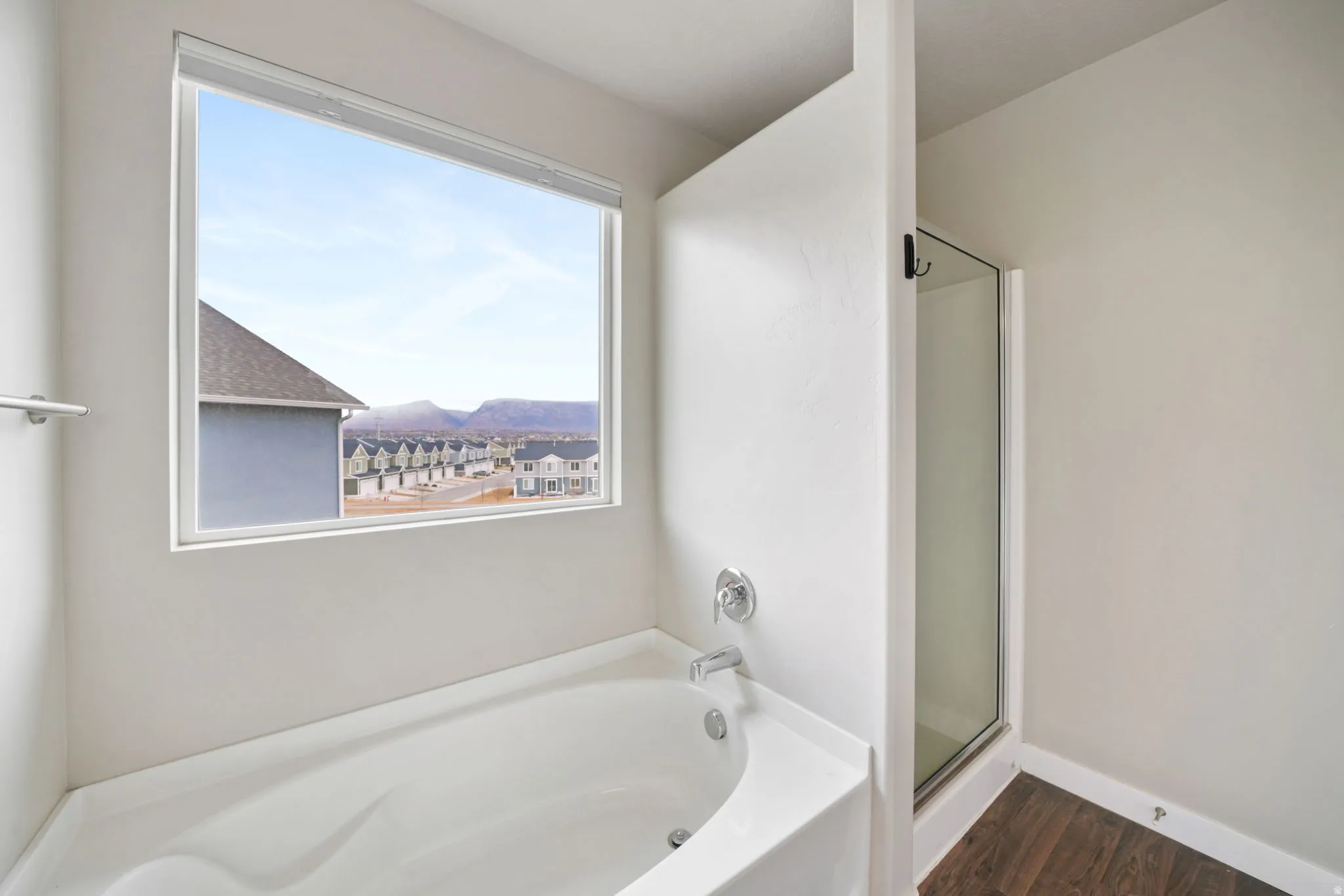 Bathroom with a stall shower, a garden tub, a mountain view, and dark wood-type flooring