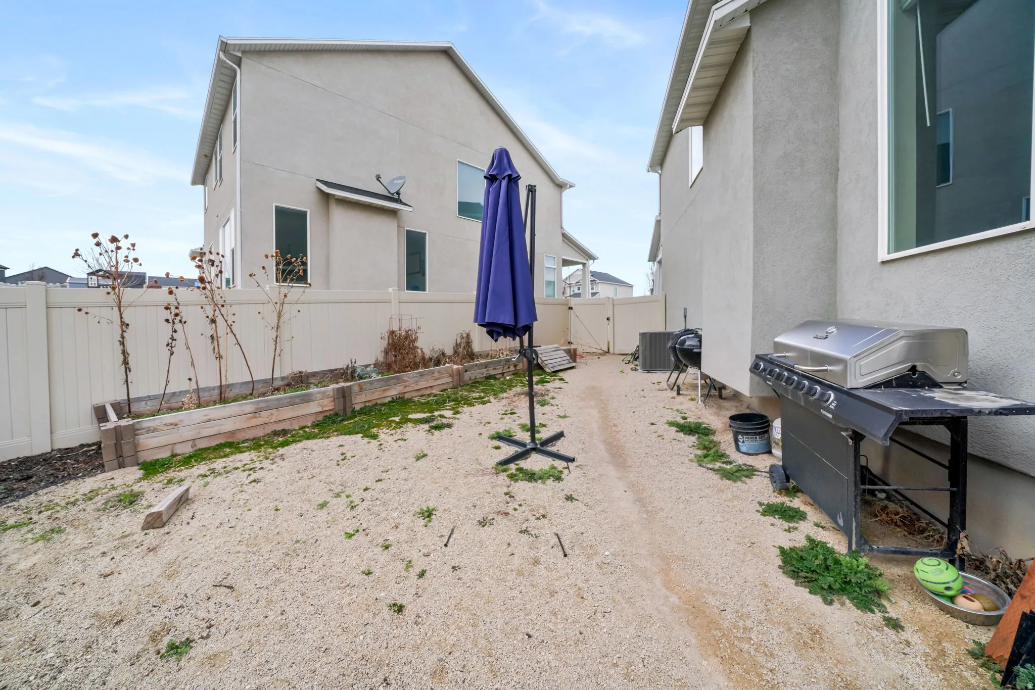 View of side of home with stucco siding, a gate, and a fenced backyard