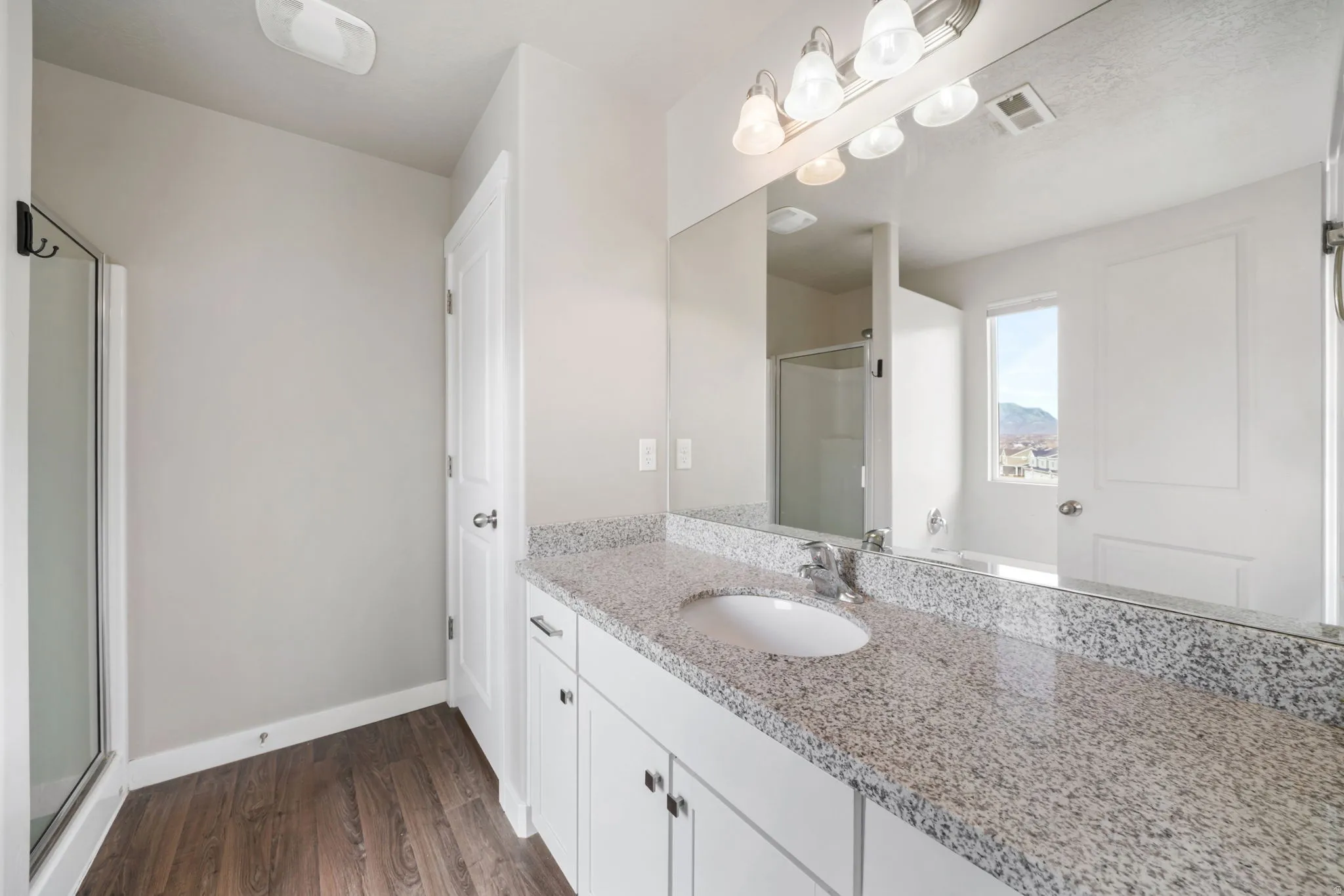 Bathroom featuring a stall shower, vanity, and dark wood-style flooring