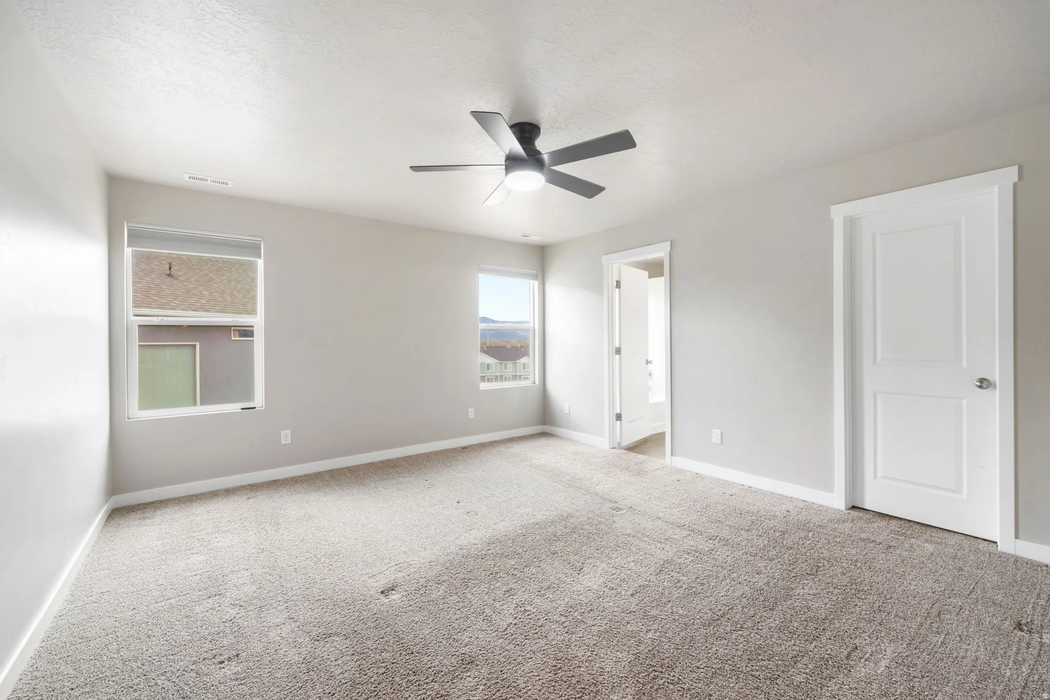 Unfurnished bedroom with carpet flooring, a ceiling fan, and ensuite bath