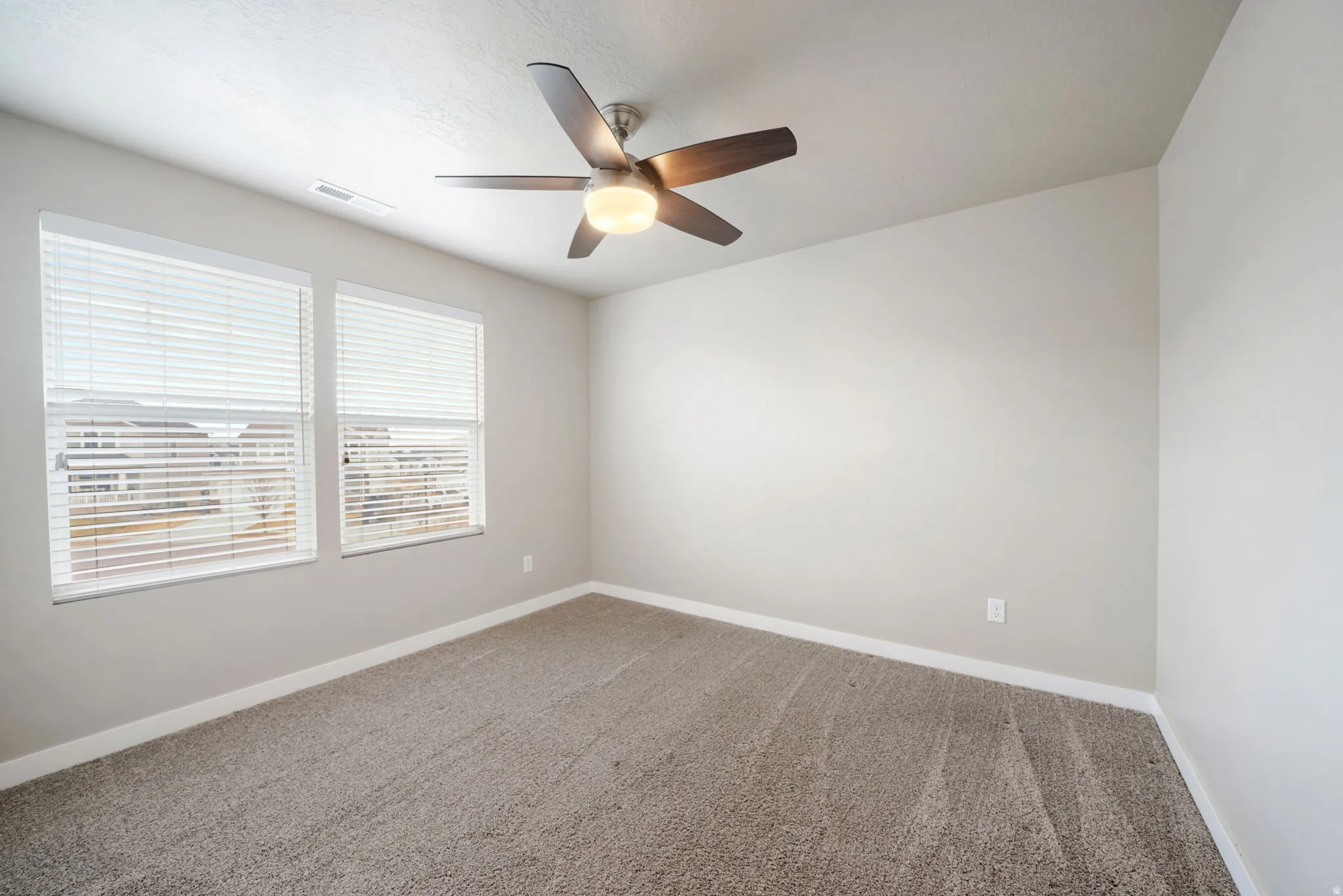 Carpeted empty room featuring baseboards and a ceiling fan