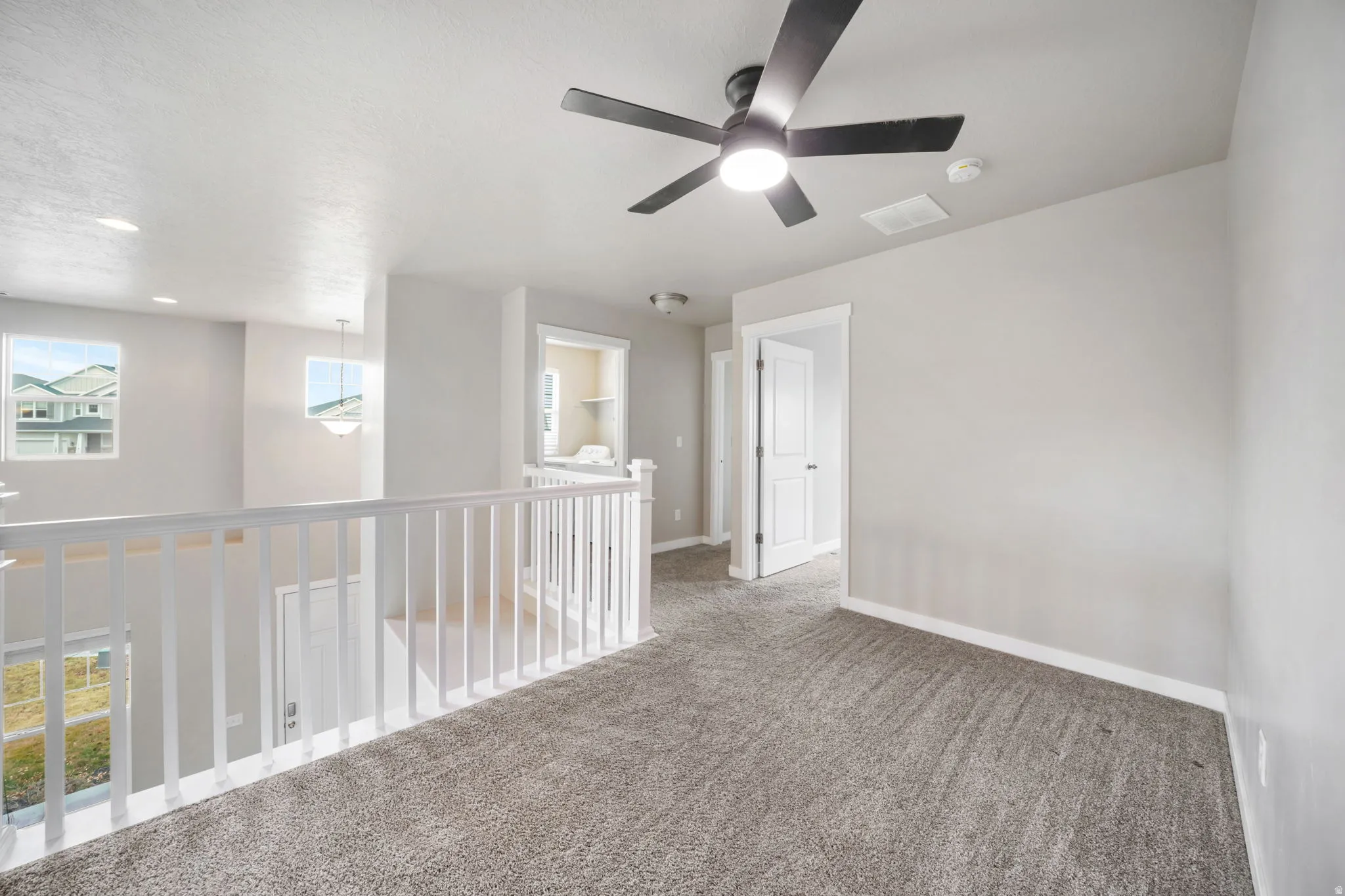 Empty room featuring carpet flooring, ceiling fan, and a smoke detector