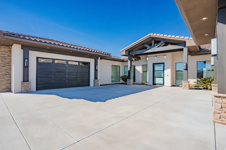 View of front of home with stone siding, a tile roof, stucco siding, and concrete driveway