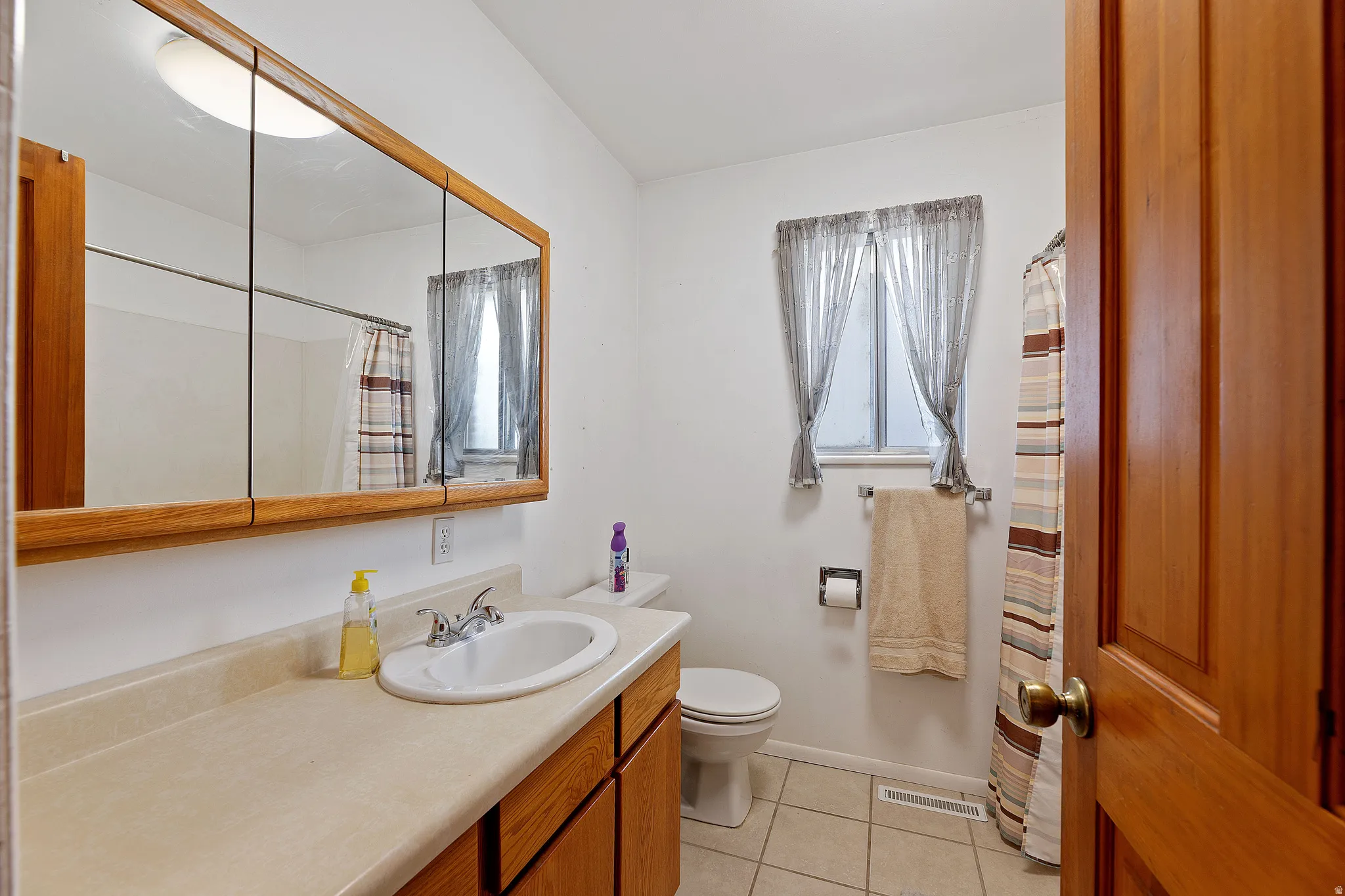 Bathroom featuring a shower with curtain, vanity, and light tile patterned floors