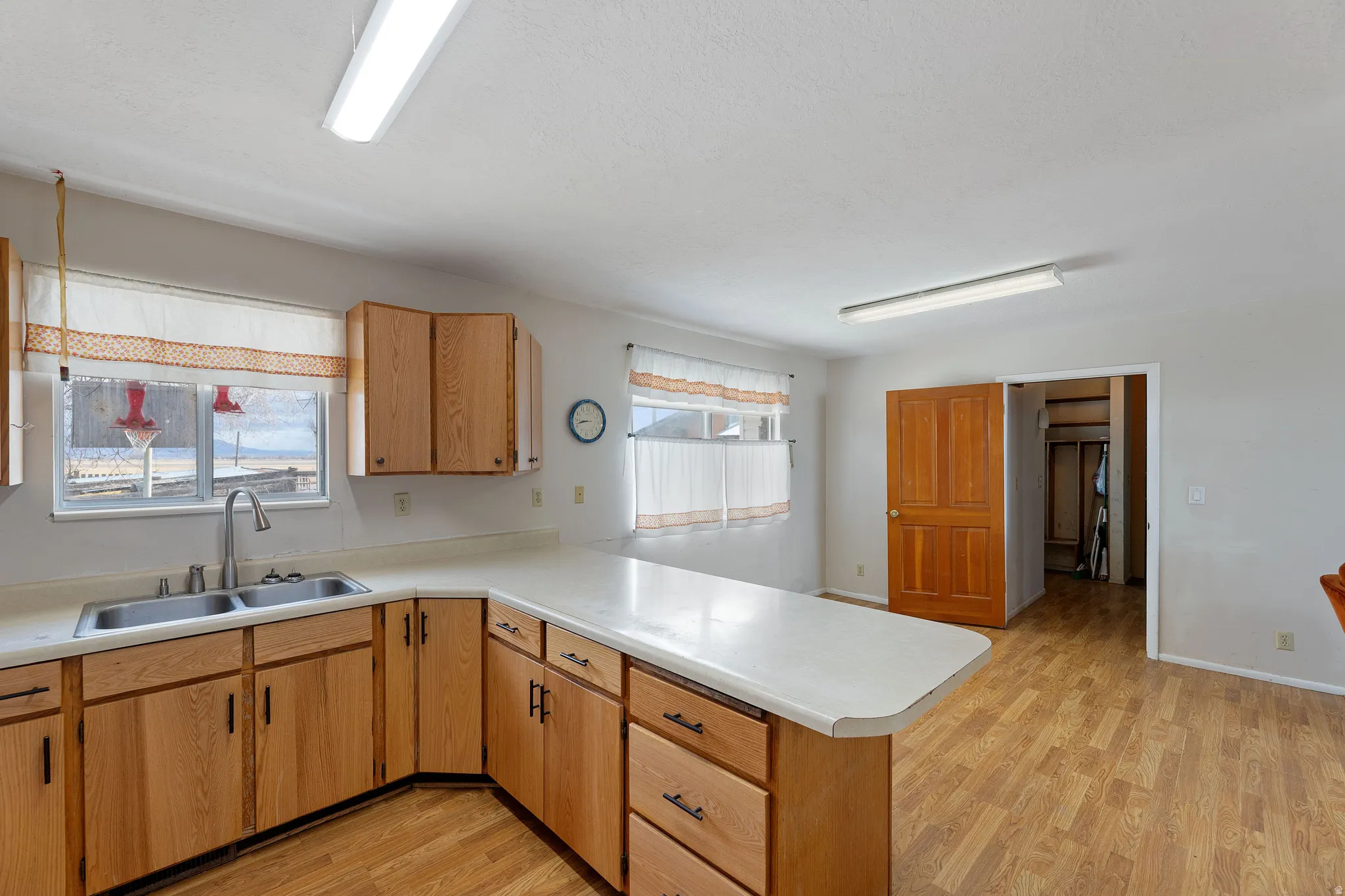 Kitchen with a peninsula, light wood finished floors, and light countertops