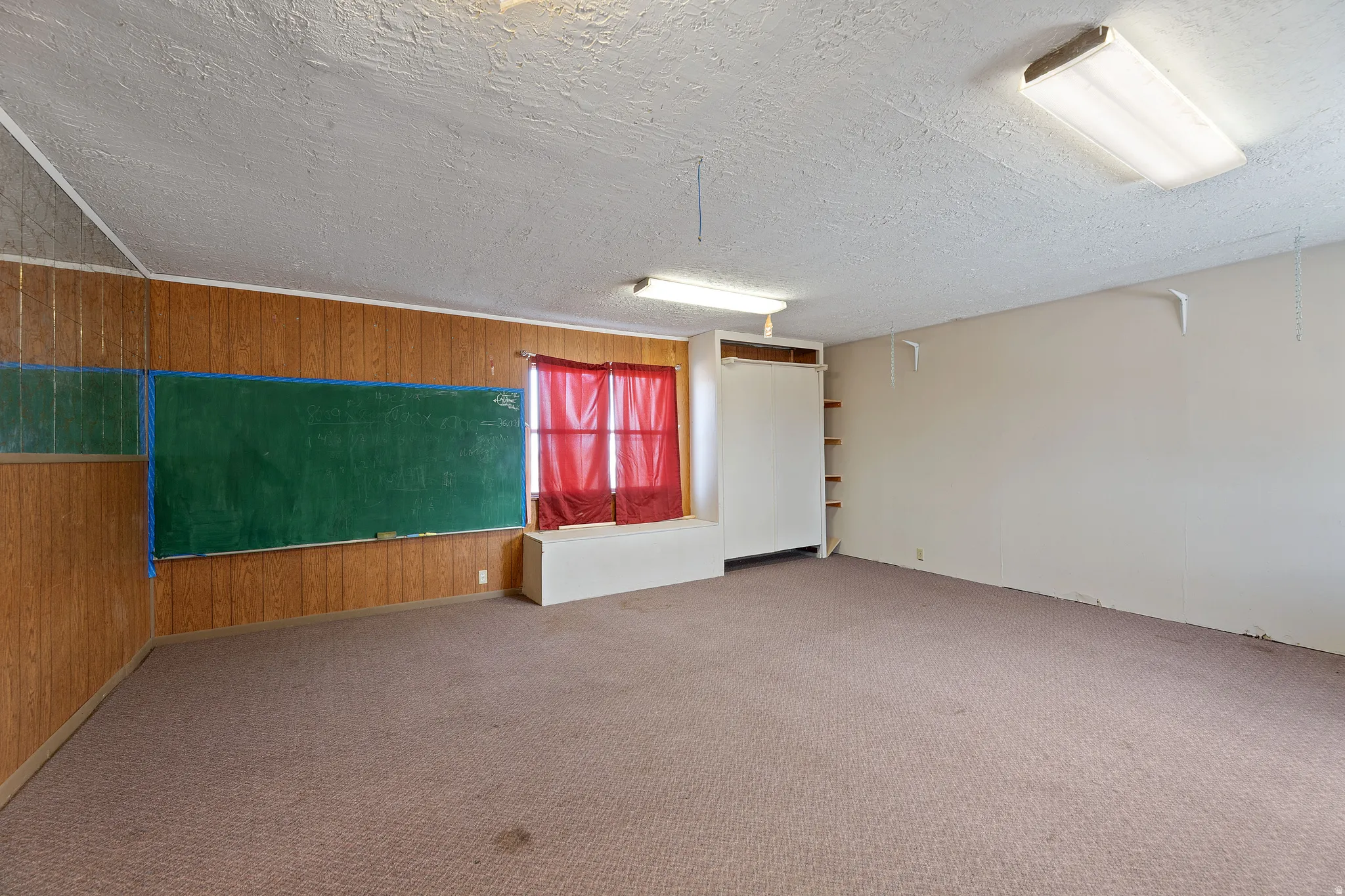 Unfurnished room with wood walls, carpet flooring, and a textured ceiling