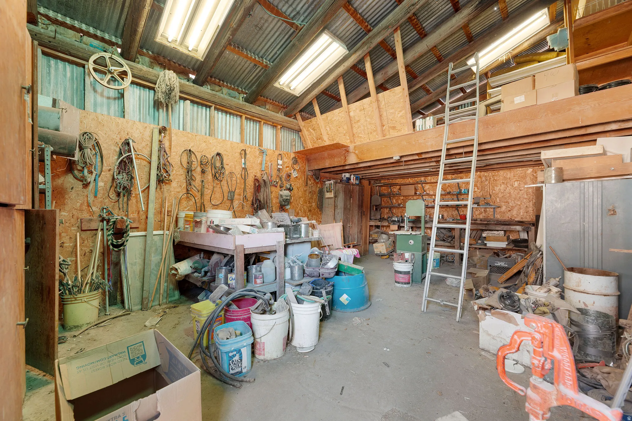 Misc room with unfinished concrete flooring, a high ceiling, and a workshop area