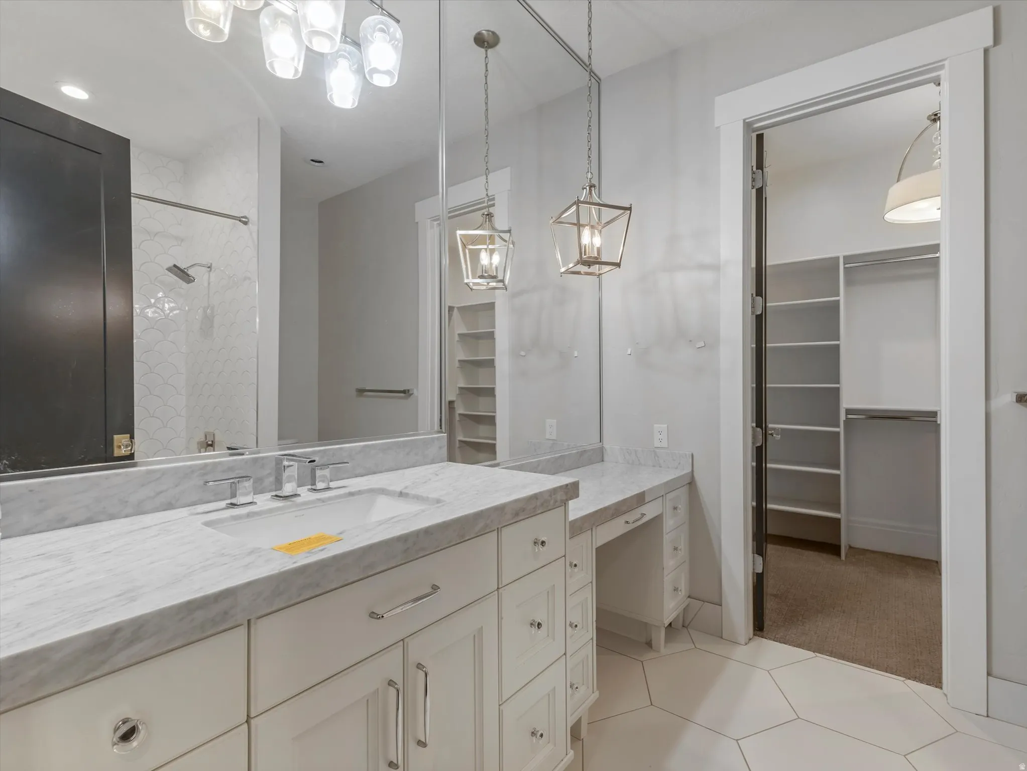 Full bath with a spacious closet, vanity, tiled shower, light tile patterned floors, and light colored carpet