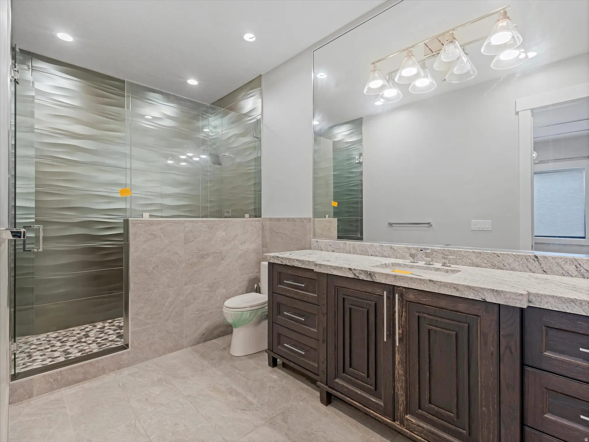 Bathroom with a shower stall, vanity, tile walls, and recessed lighting