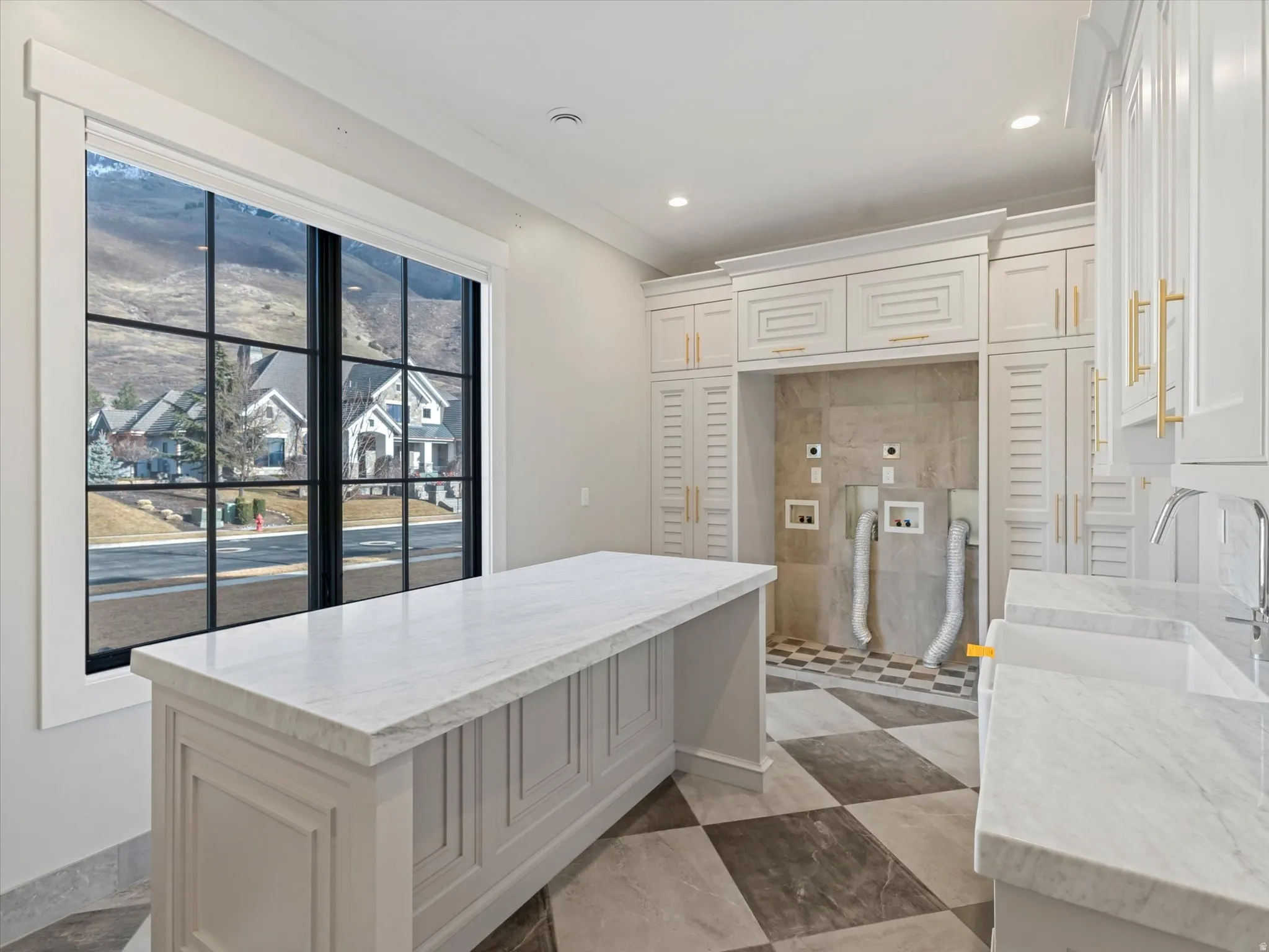 Main floor double laundry with light stone countertops, white cabinetry, recessed lighting, and a kitchen island