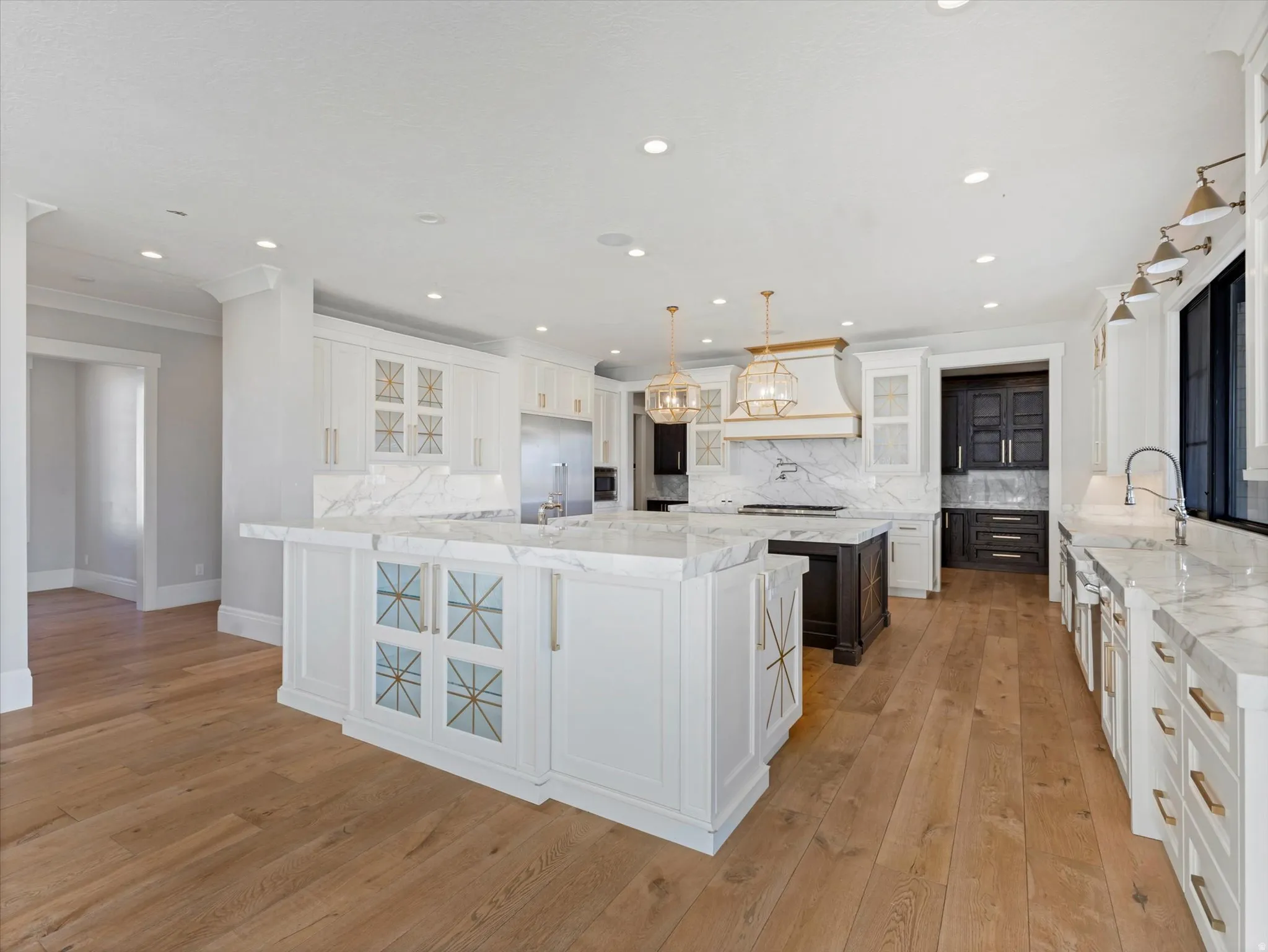 Kitchen featuring pendant lighting, light stone counters, light wood-style flooring, decorative backsplash, and dual tone cabinetry