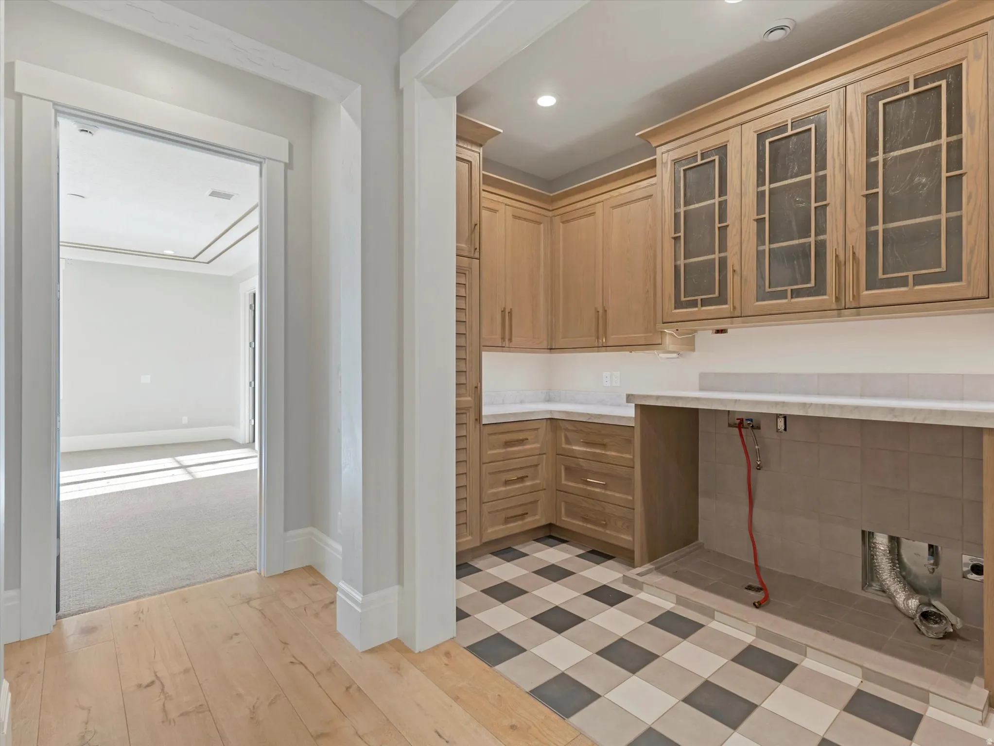 Laundry area featuring glass insert cabinets, light wood finished floors, light countertops, recessed lighting, and light wood finish cabinetry