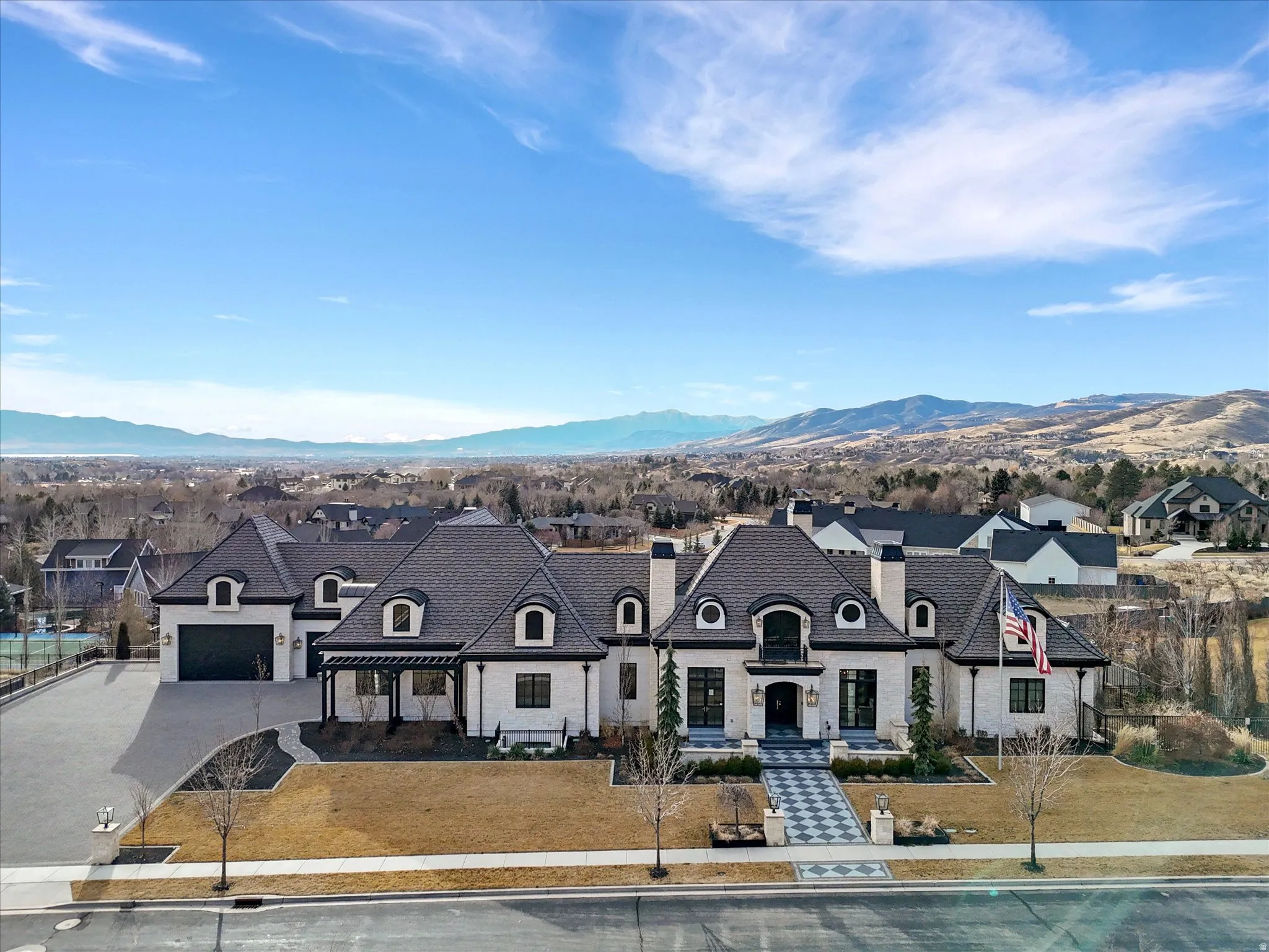 French country inspired facade featuring concrete driveway, a chimney, stone siding, and a mountain view
