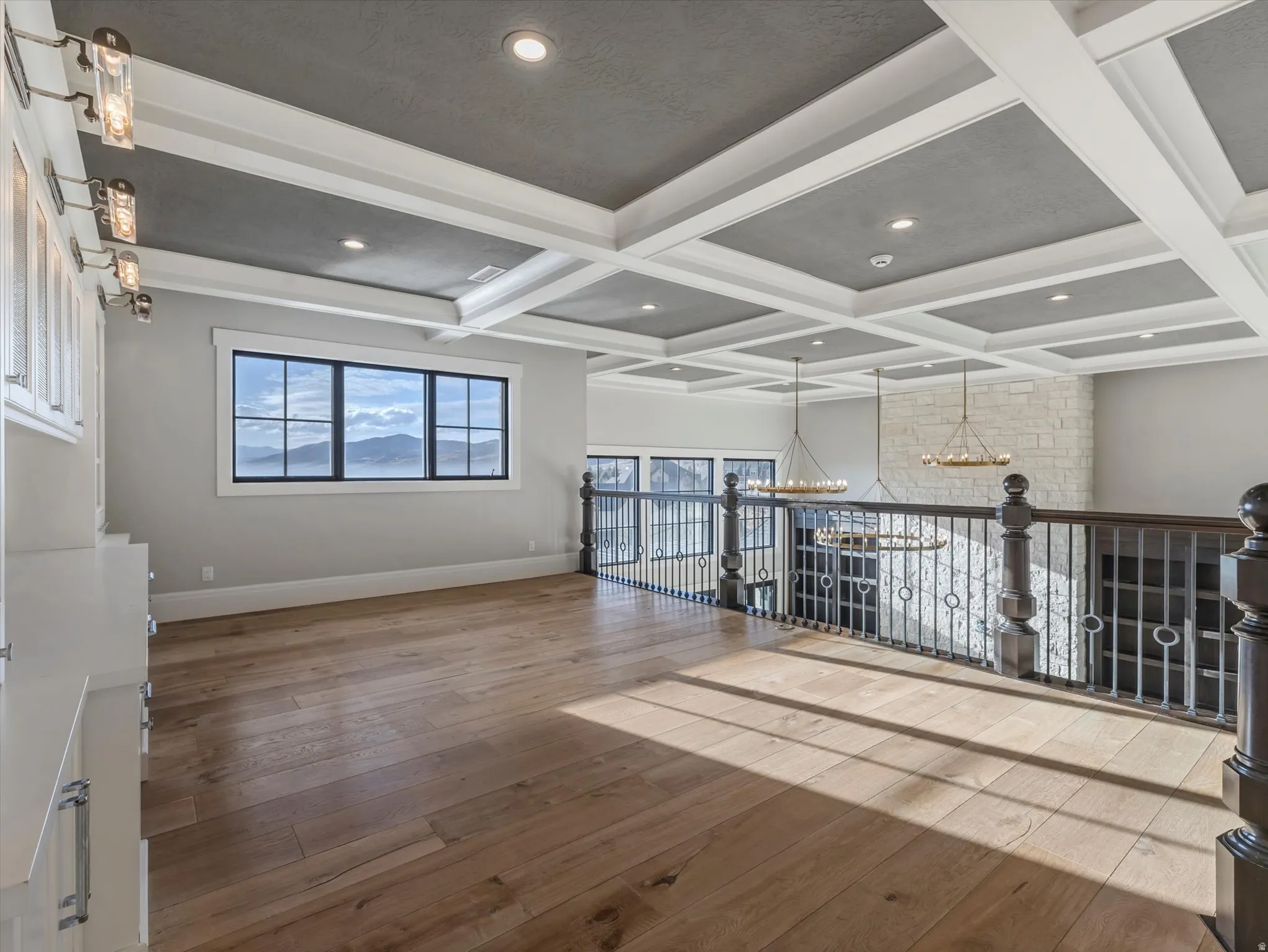 Spare room featuring coffered ceiling, suspended lighting, and light wood finished floors