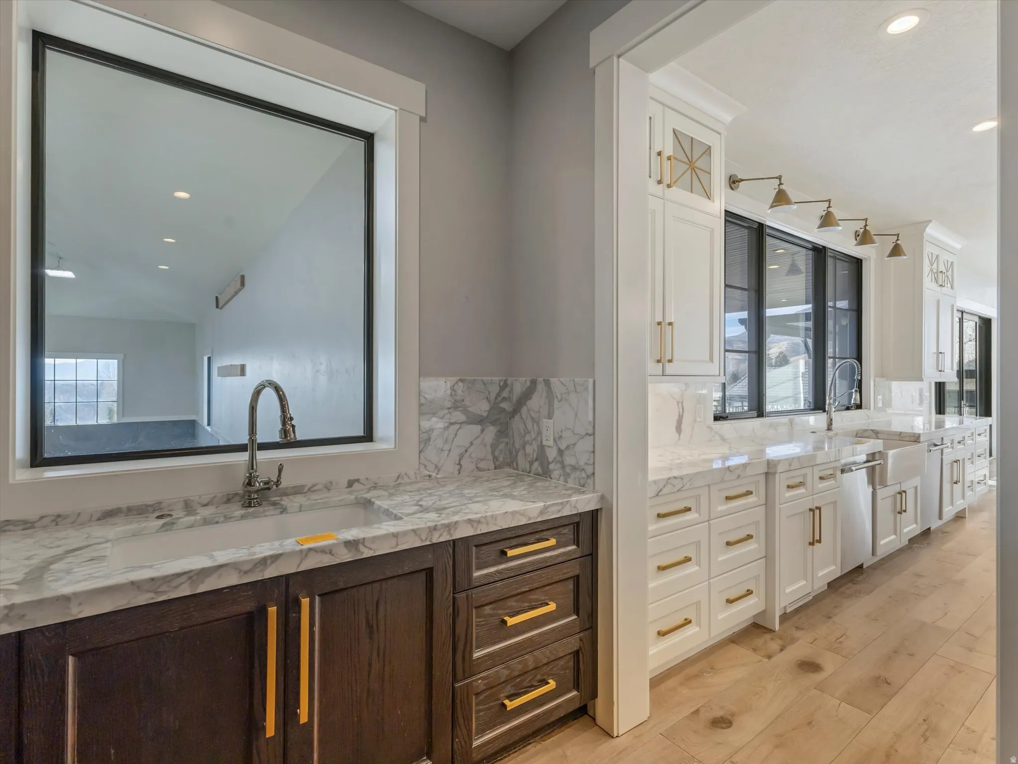 Pantry sink view into the kitchen and basketball court featuring recessed lighting, two vanities, plenty of natural light, and light wood-style floors