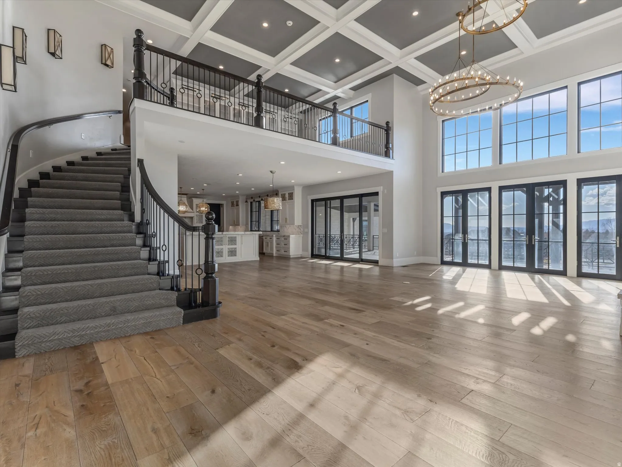 Unfurnished living room with suspended lighting, coffered ceiling, light wood finished floors, and french doors