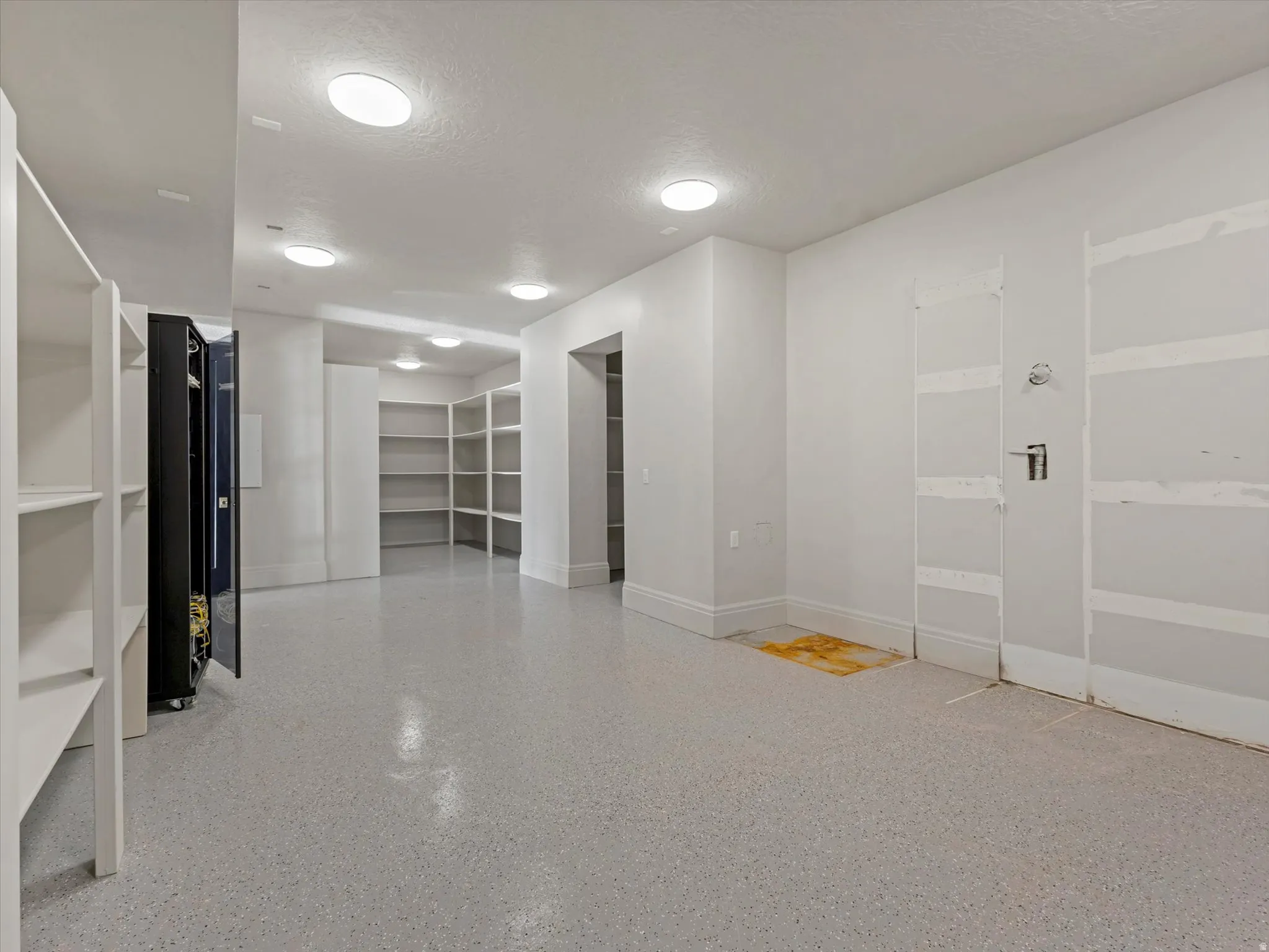 Unfurnished storage room with a textured ceiling and dark speckled floor