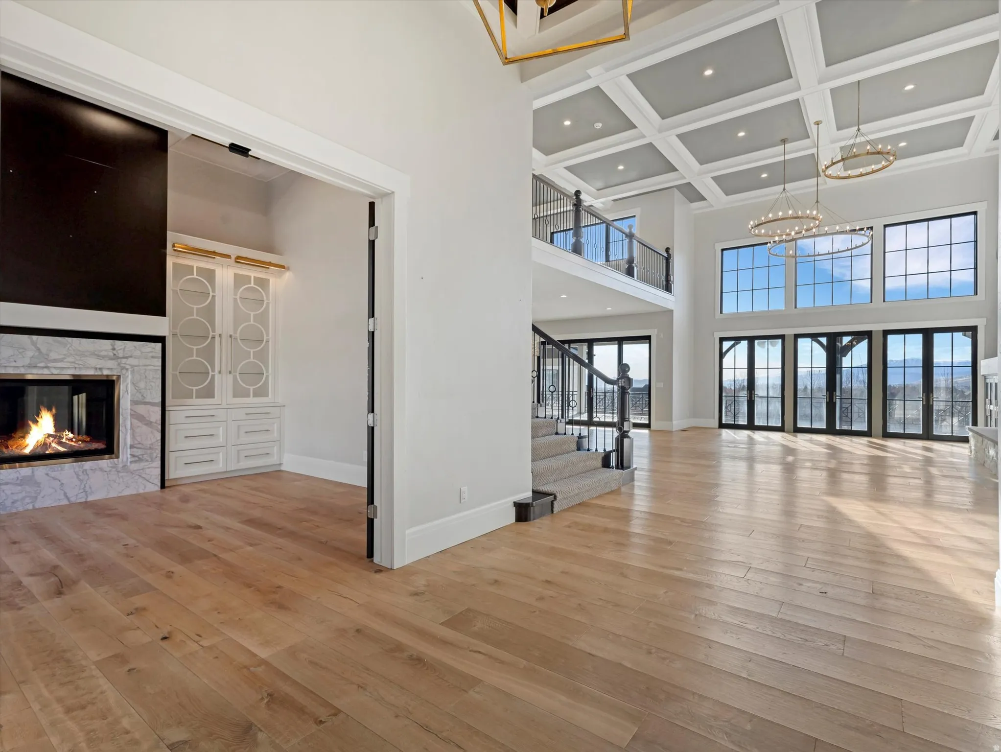 Unfurnished living room with recessed lighting, coffered ceiling, a high end fireplace, light wood-style flooring, and french doors