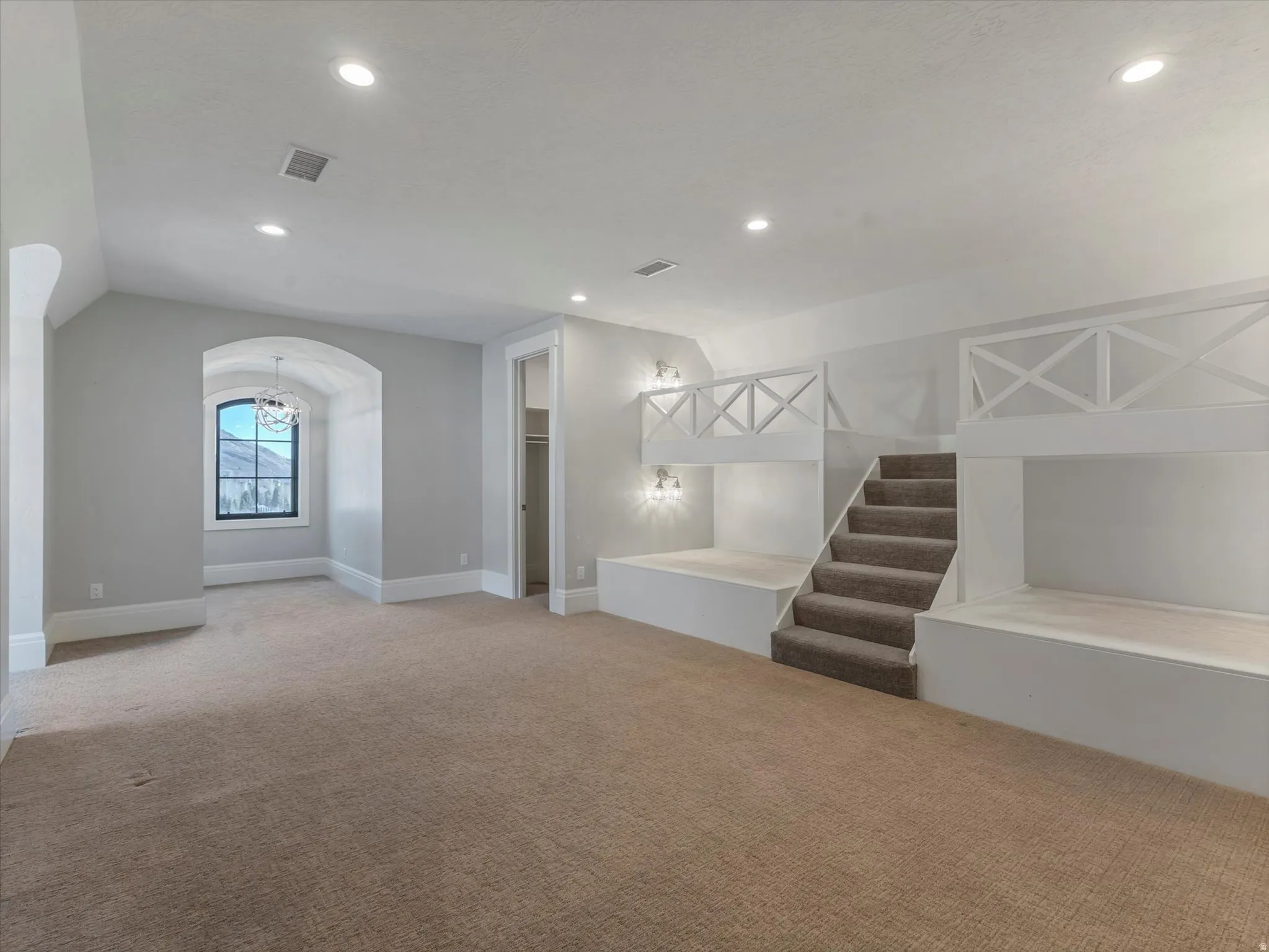Bedroom featuring carpet, arched walkways, and suspended lighting
