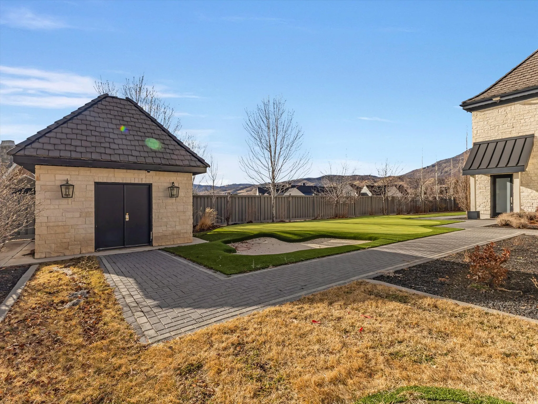 Fenced backyard with an outbuilding and putting green.