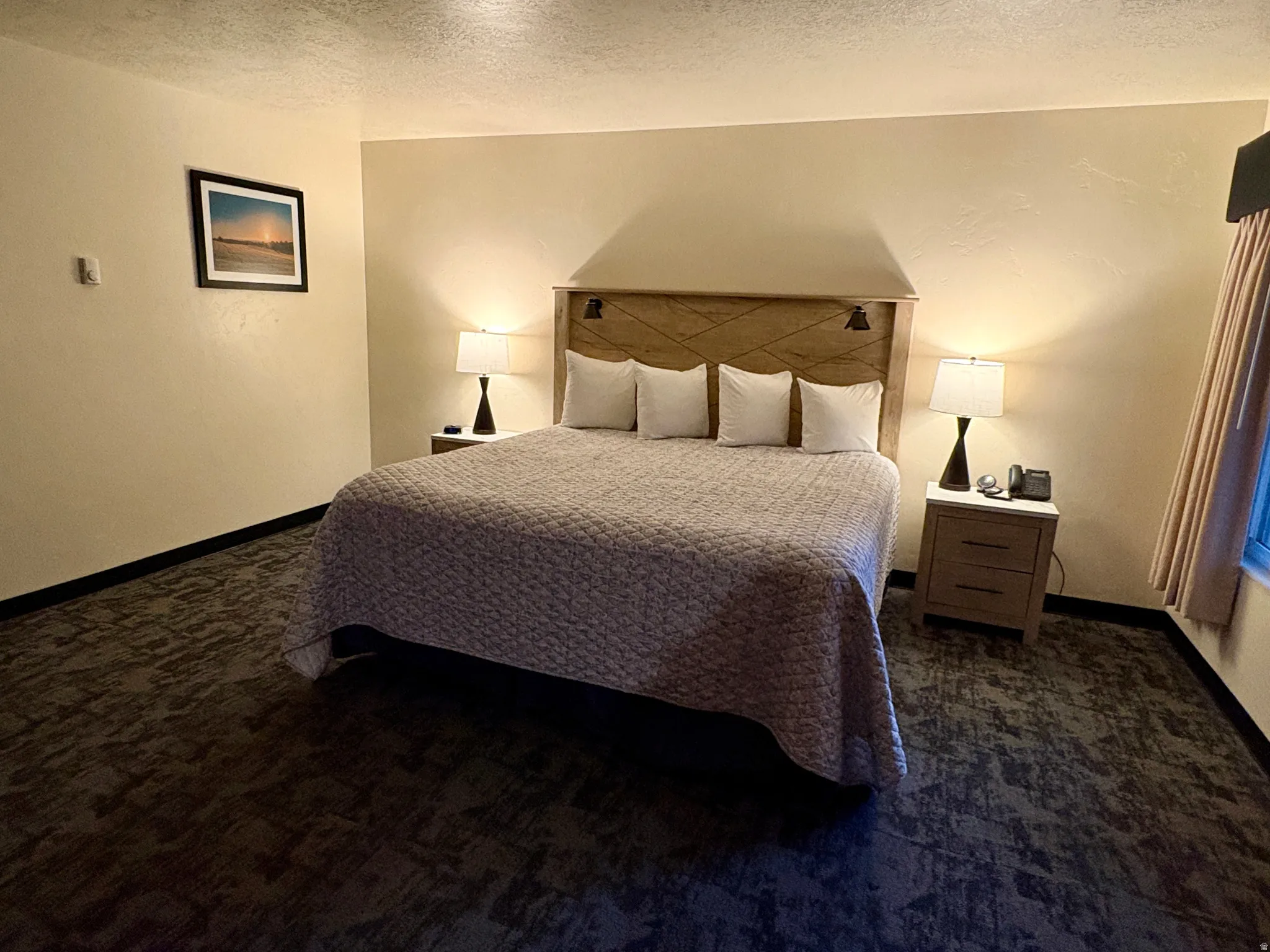 Bedroom with a textured ceiling and dark colored carpet