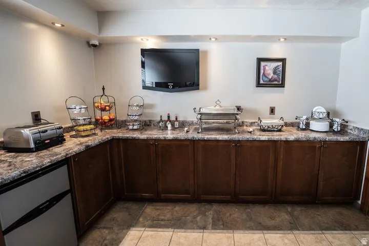 Bar area with dark wood finish cabinetry, recessed lighting, and dark stone counters