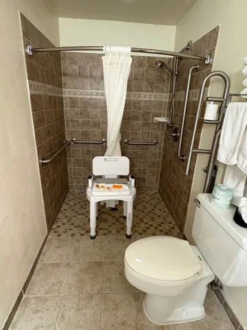 Full bathroom featuring a textured wall, a shower stall, and light tile patterned flooring
