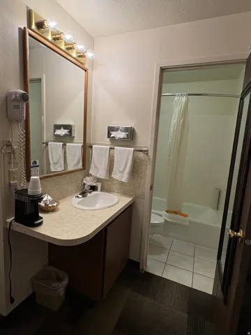 Full bath featuring a textured ceiling, shower / bath combination with curtain, vanity, a textured wall, and light tile patterned floors
